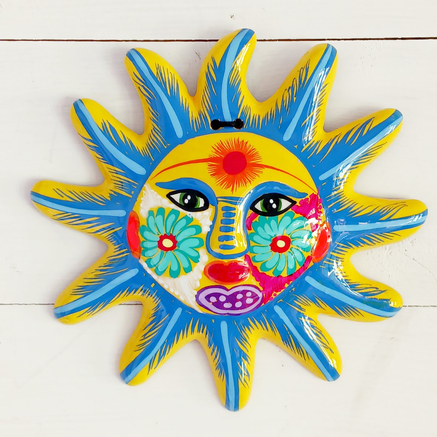 Bring a burst of colour and joy into your space with this sunny, vibrant wall plaque! Expertly hand-painted in the bold, traditional style of Xalitla, Guerrero, Mexico, this decorative piece radiates cultural charm. The vivid colors and striking glaze add depth and personality, making it a standout feature in any room. With two convenient holes for easy hanging, it’s ready to brighten your home with authentic folk art flair.