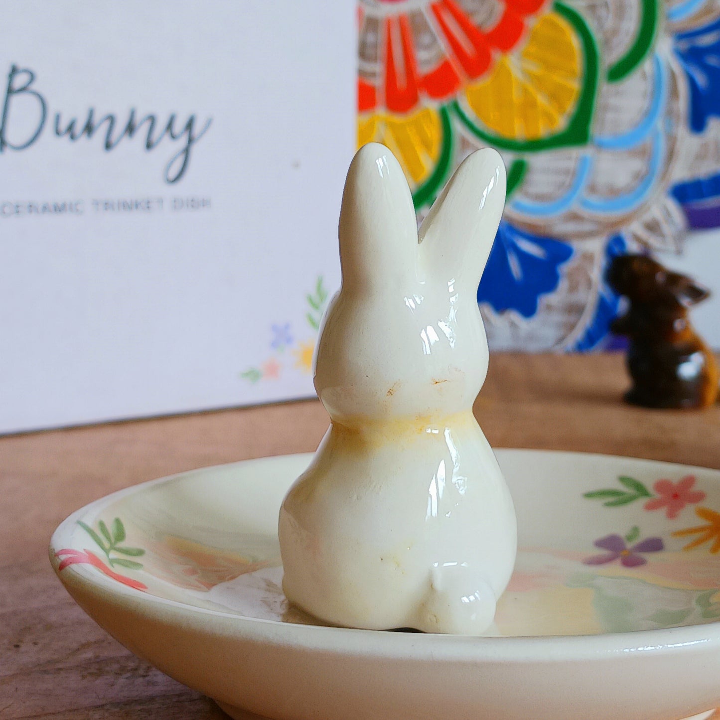 Add a charming touch of spring to your space with this Bunny Floral Ceramic Trinket Dish. Featuring a delicate floral design and a sweet bunny illustration at the center, this dish is perfect for holding jewellery, keys, coins, or other small treasures. Whether placed on a dresser, vanity, or bedside table, it combines functionality with fun and festive decor, making it an ideal gift or seasonal accent.
