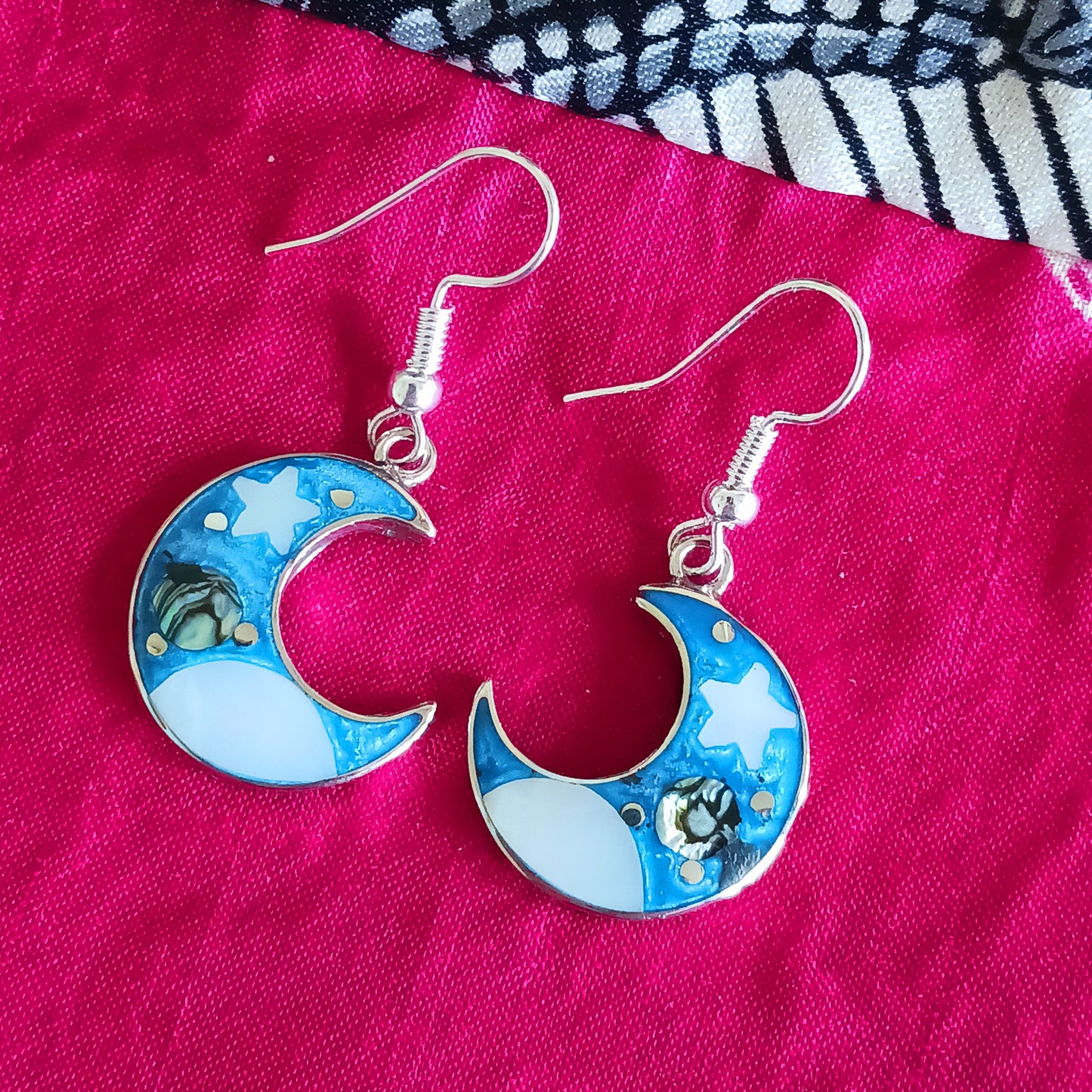 This set of beautiful celestial themed earrings are hand crafted in Taxco, Mexico. Utilising a eye-catching crescent moon design created using traditional Alpaca steel as the frame. These earrings have a celestial theme created using dyed, iridescent abalone shell.