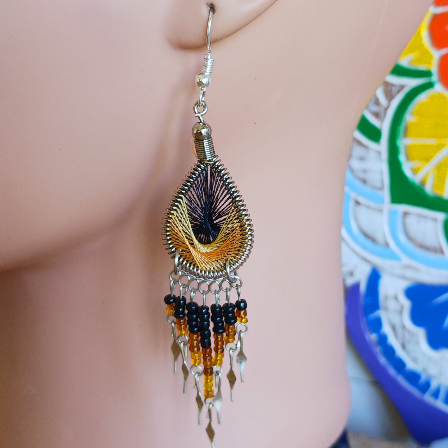 These beautiful and eye-catching earrings are handmade in Peru and feature an array of gorgeous colours. A woven teardrop, similar in style to a peacock feather, is finished with co-ordinating beads and silver embellishments. Ideal for a night out or for dressing up your boho look!