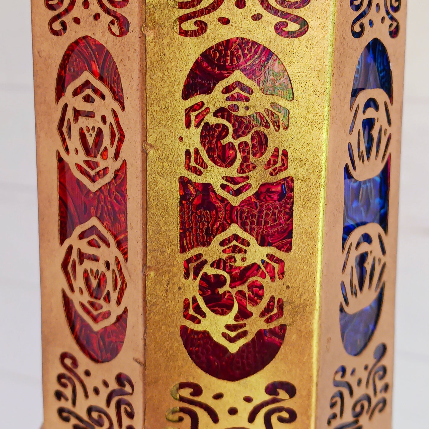Discover the enchanting seven-sided standing lantern, each side beautifully illustrating one of the unique chakra symbols. Crafted from exquisite gold metal, this lantern not only adds a touch of elegance to any space but also features a convenient bottom turn-opening door that doubles as a candle holder tray.