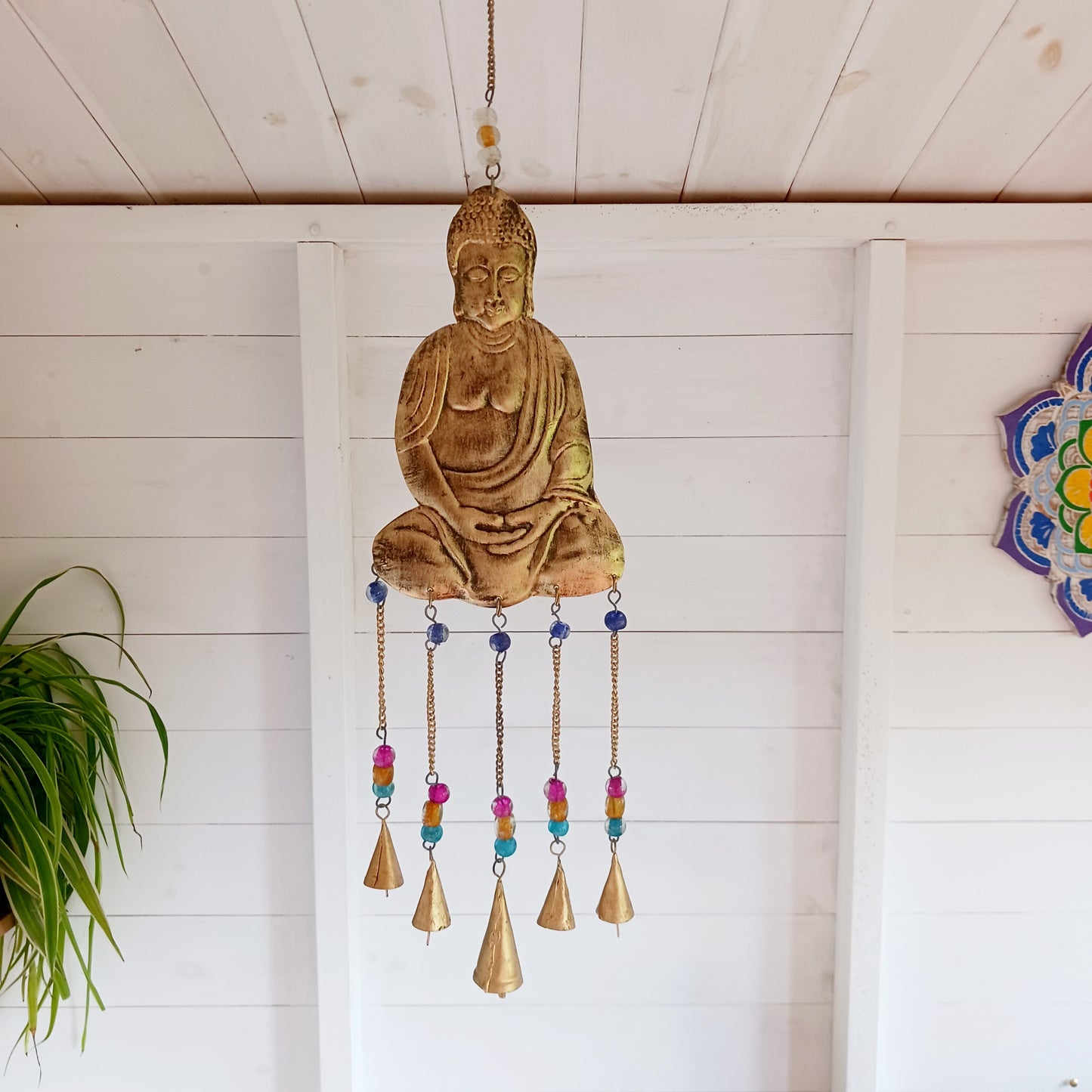This lovely Buddha 5 bell windchime will bring serenity and cultural charm to any space. Made in India from brass, this chime features a beautifully detailed Buddha adorned with colourful beads.
The five brass bells create a calming melody with every breeze, making it a perfect addition to meditation spaces, gardens, or tranquil home settings.