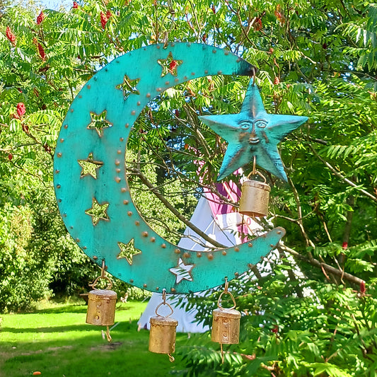 Bring a touch of celestial charm to your home with this rustic crescent moon wind chime, beautifully finished in an aged verdigris green. Handmade by skilled artisans in India, this decorative iron wall hanging features pierced star detailing, a hanging star charm and traditional Indian brass bells.