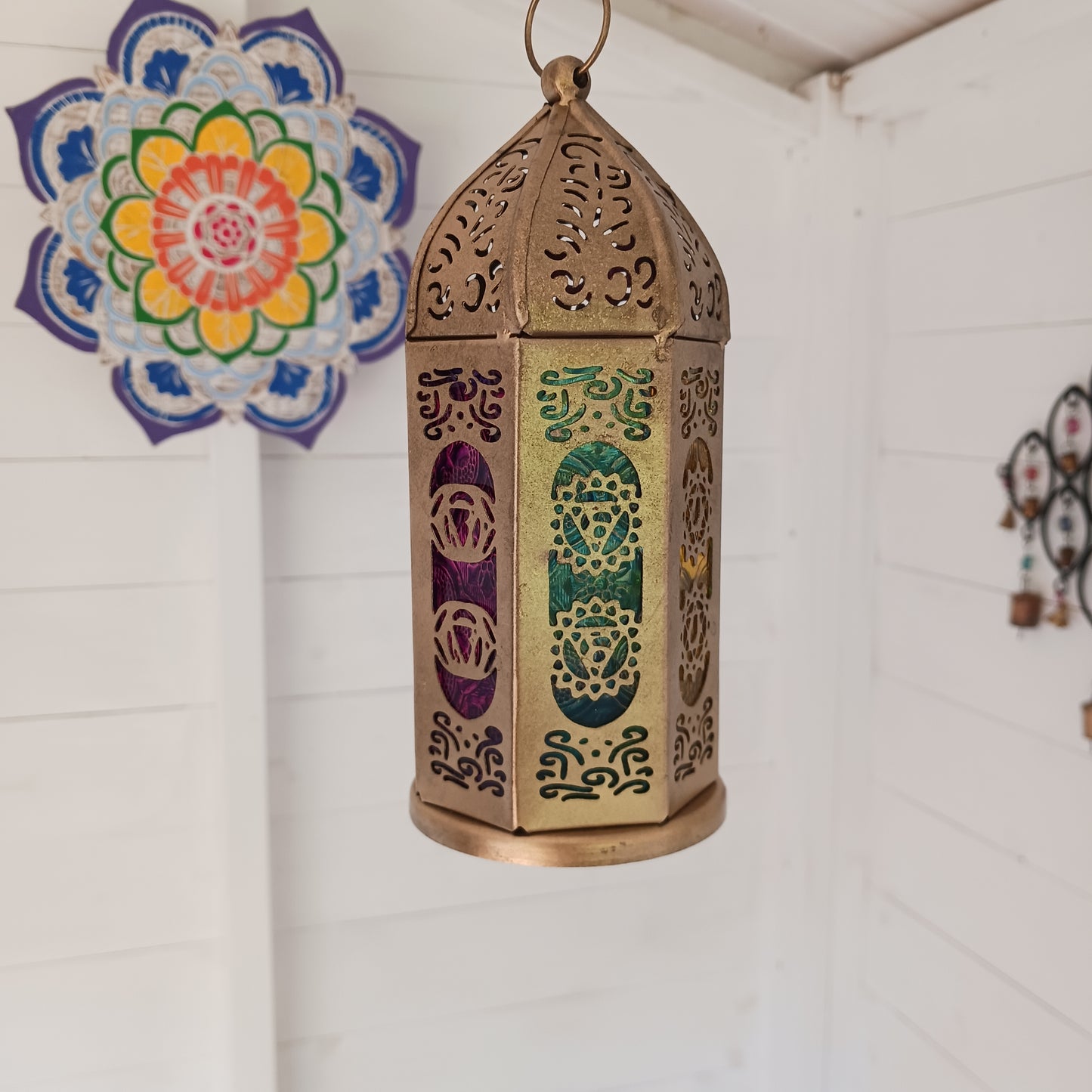 Discover the enchanting seven-sided standing lantern, each side beautifully illustrating one of the unique chakra symbols. Crafted from exquisite gold metal, this lantern not only adds a touch of elegance to any space but also features a convenient bottom turn-opening door that doubles as a candle holder tray.