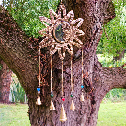 Introduce a radiant touch to any space in your home or garden with this sun and moon Indian chime featuring a small mirror and five delicate bells. The brass sun and moon design symbolizes harmony between opposing forces - light and darkness, day and night. A small reflective mirror at the centre enhances the aesthetic while adding a touch of mysticism. The five hanging bells, accented with colourful beads, offer a gentle chime, creating a soothing atmosphere whether indoors or outdoors.