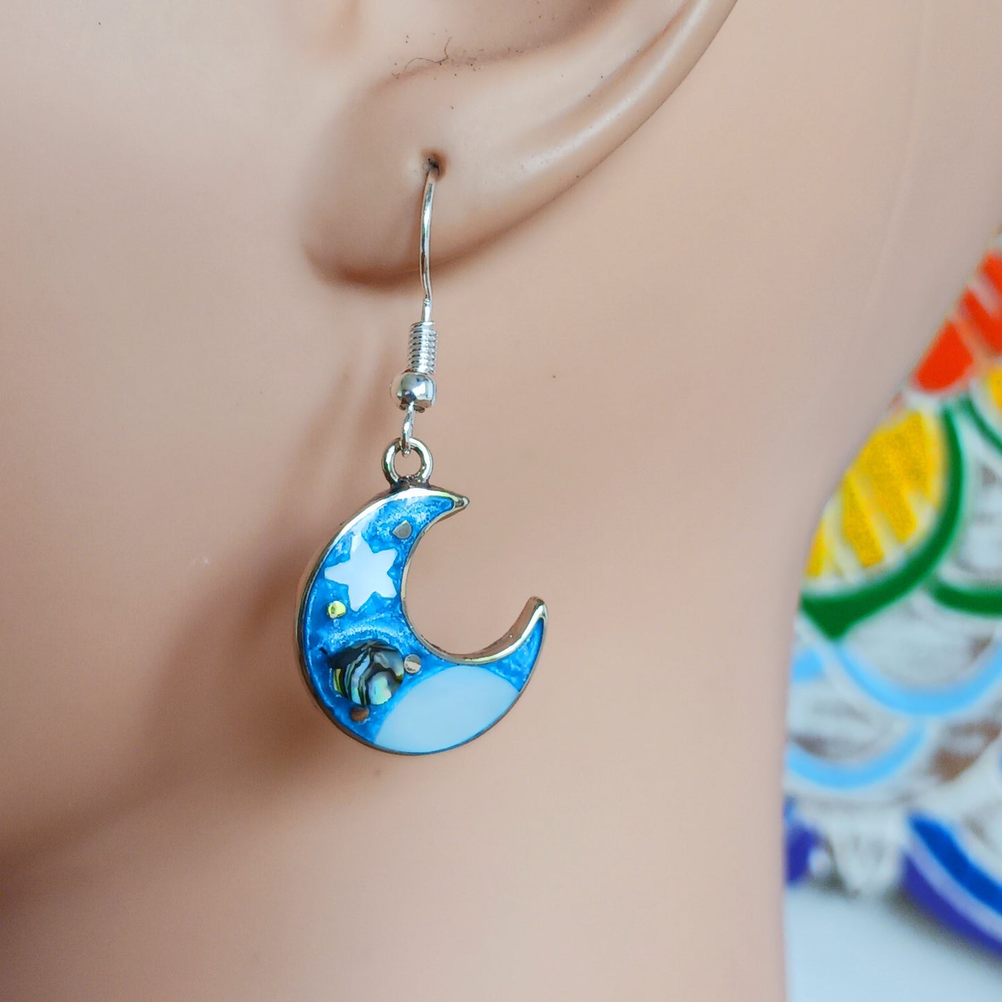 This set of beautiful celestial themed earrings are hand crafted in Taxco, Mexico. Utilising a eye-catching crescent moon design created using traditional Alpaca steel as the frame. These earrings have a celestial theme created using dyed, iridescent abalone shell.