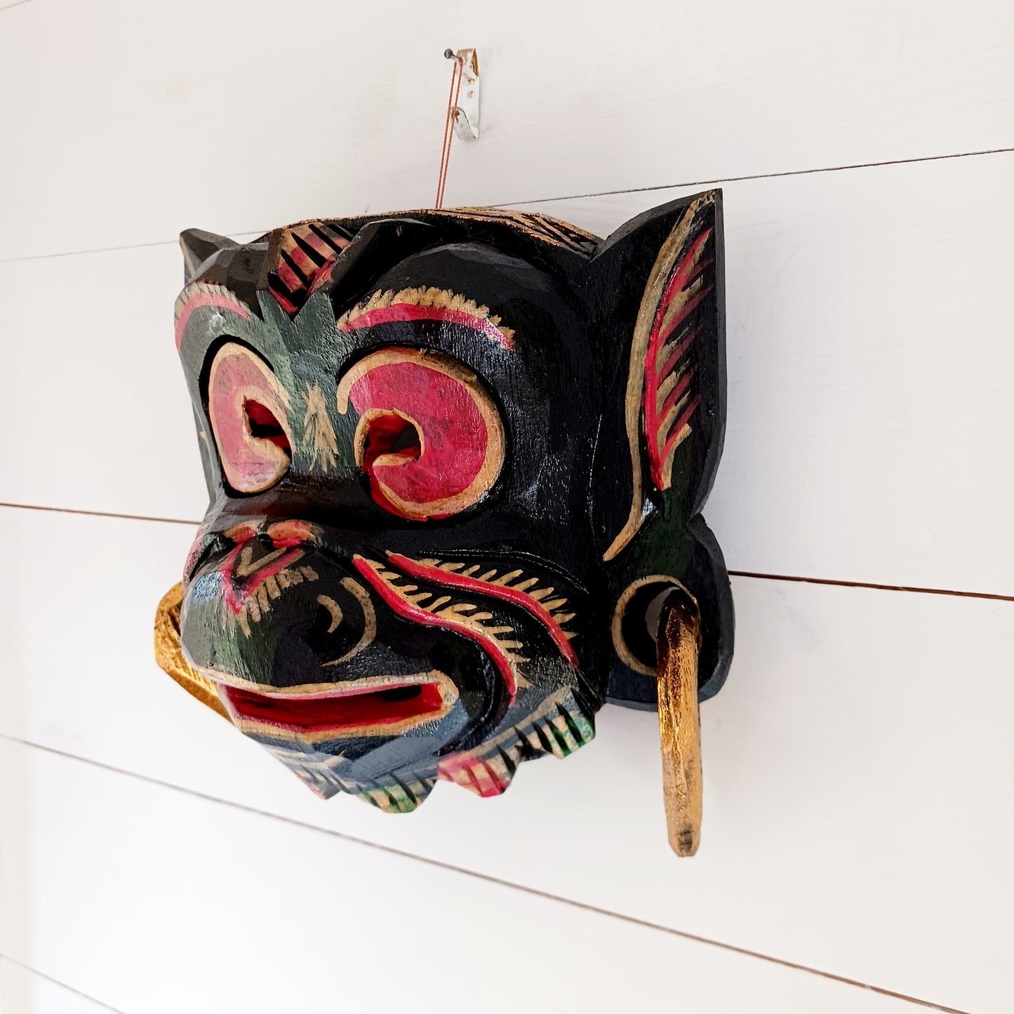 This hand carved and hand painted mask depicts Hanuman, the monkey god. He is integral to the Hindu tale of Ramayana, aiding Rama in the heroic rescue of his wife Sita.