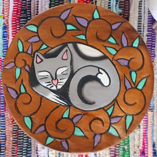 This lovely little handmade, carved and painted stool is Fairtrade from Thailand. The top of this stool has been carefully hand carved and then painted to show a peacefully curled, sleeping cat surrounded by comfy leaves. These cheeky little items are very versatile making great stools for little bums or as tiny tables to add accent to your home.