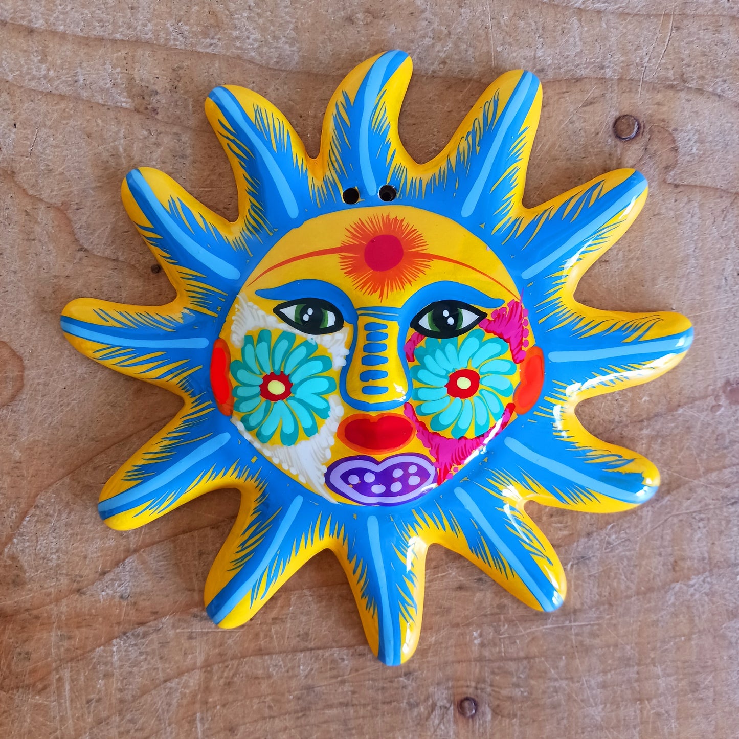 Bring a burst of colour and joy into your space with this sunny, vibrant wall plaque! Expertly hand-painted in the bold, traditional style of Xalitla, Guerrero, Mexico, this decorative piece radiates cultural charm. The vivid colors and striking glaze add depth and personality, making it a standout feature in any room. With two convenient holes for easy hanging, it’s ready to brighten your home with authentic folk art flair.