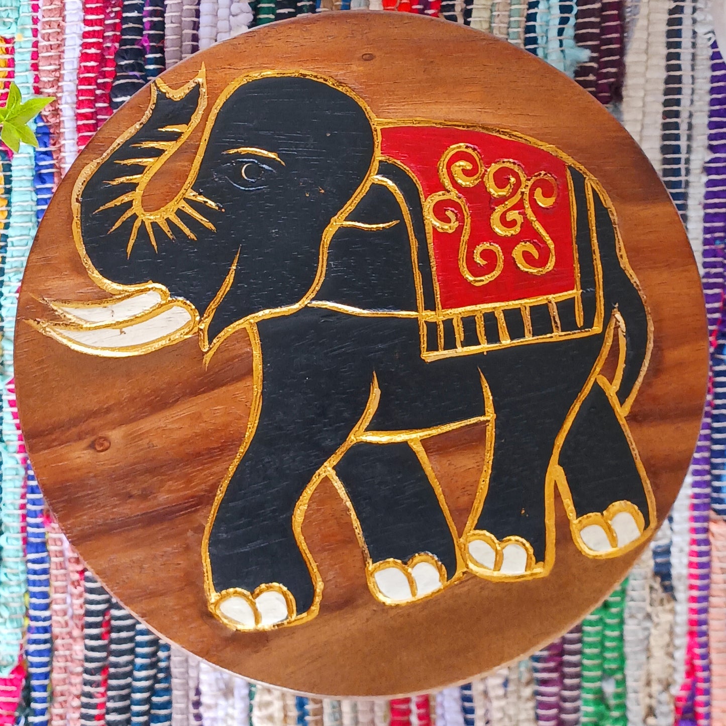 This sturdy little foot stool is from northern Thailand and features a lovely hand carved image of a festival elephant with gold paint detail. The stool is made from sustainable acacia wood. It is strong enough to sit on, use as a plant stand or purely for decoration.