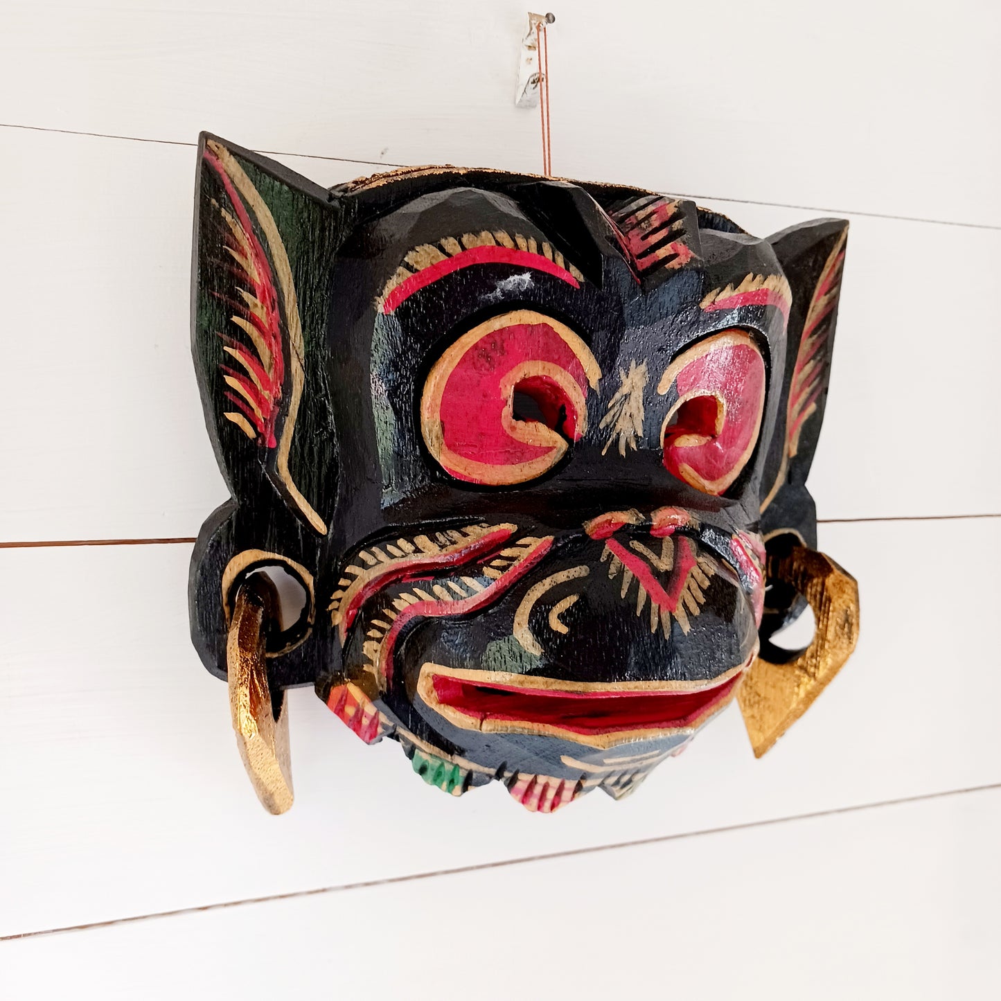 This hand carved and hand painted mask depicts Hanuman, the monkey god. He is integral to the Hindu tale of Ramayana, aiding Rama in the heroic rescue of his wife Sita.
