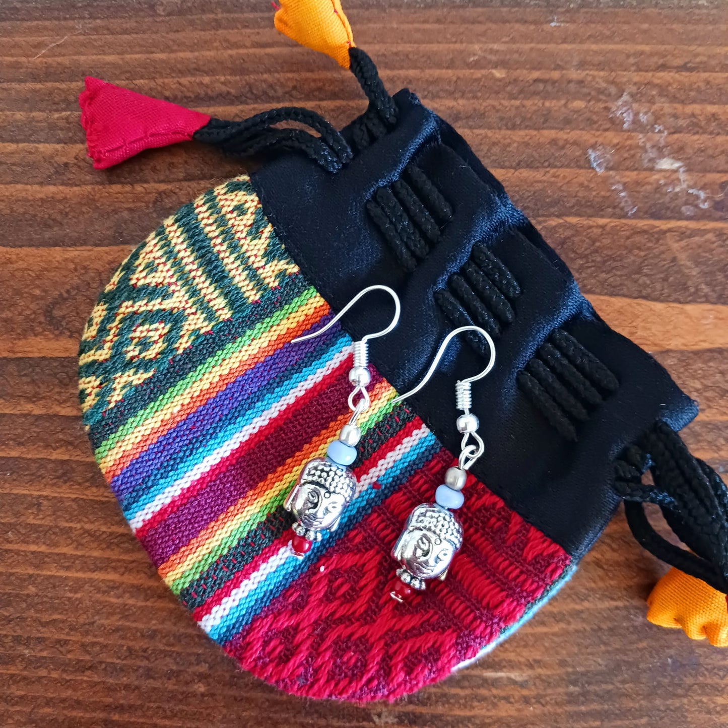These pretty and intricate dangly earrings feature Buddha heads, decorative beads in blue and red and are hung on silver plated hooks. Gifted in a traditional Tibetan pouch.