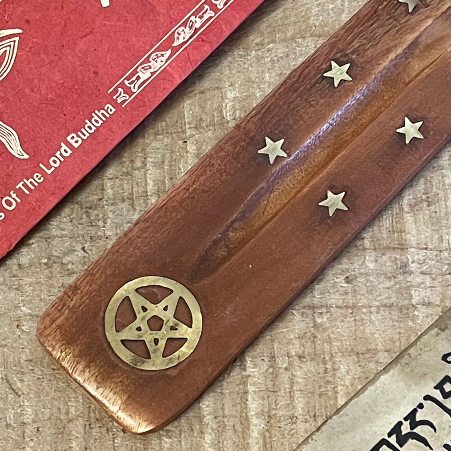 This popular shoehorn-style incense holder combines functionality with a mystical aesthetic, crafted from durable mango wood. The ash catcher features brass inlays of stars and a pentacle, symbolizing protection and balance, making it perfect for those who value spiritual symbolism. Its gently curved design securely holds incense sticks, while the wooden body catches ash as it falls, keeping your surfaces clean.