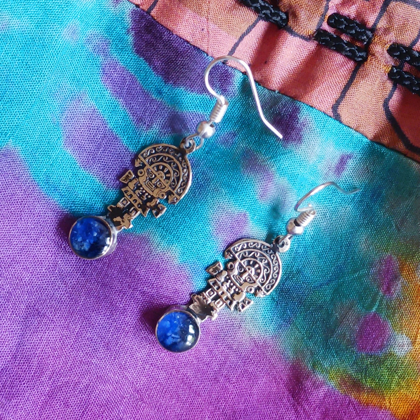 These intricate earrings feature a tiny image of the Tumi, a type of ceremonial knife used in ancient Peru by the Moche culture. &nbsp;They feature a mythical character usually identified with the god Naymlap.&nbsp;  All hooks are silver plated and these earrings come with crushed lapis lazuli stone.  Ideal for a night out, for dressing up your boho look or as a gift for family or friends.