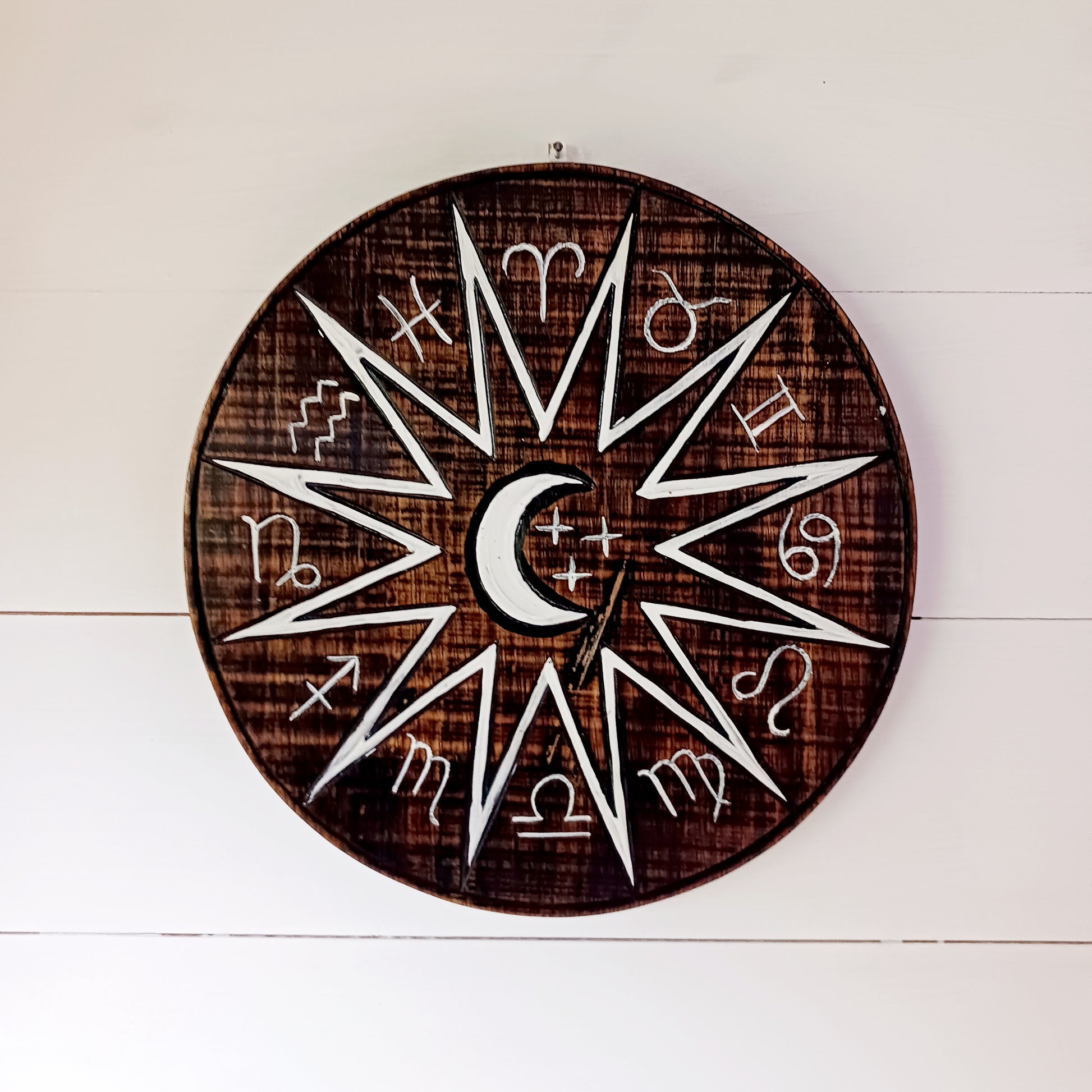 Hand carved and hand painted, this wooden wall plaque features a crescent moon and zodiac symbols design. A unique plaque for your garden.