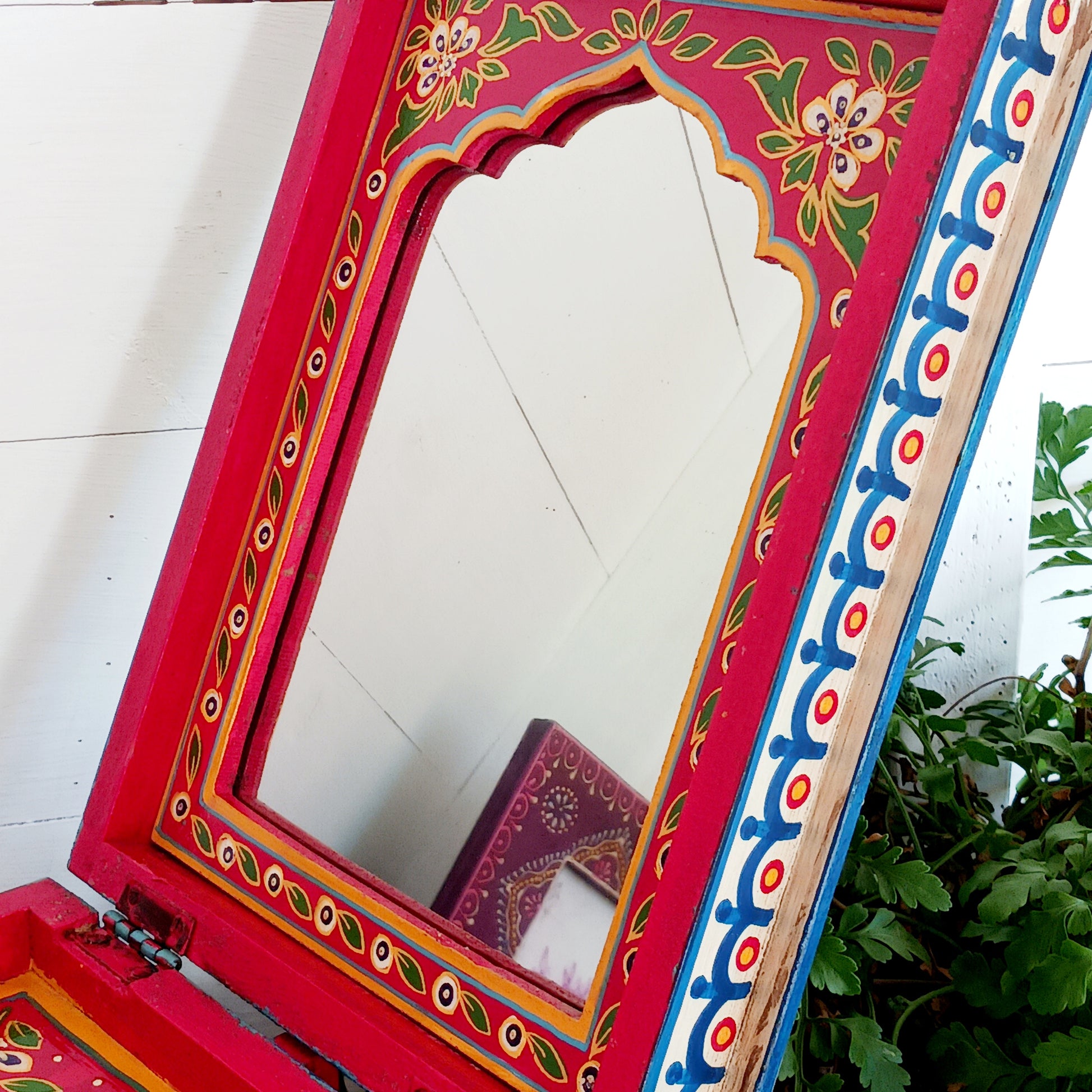 A beautiful peacock design, hand painted jewellery box in a palette of regal reds and blues made from sustainable mango wood.  This lovely box comprises a top opening section with mirror, and a single drawer; two useful compartments, accessed with discreet round knobs.