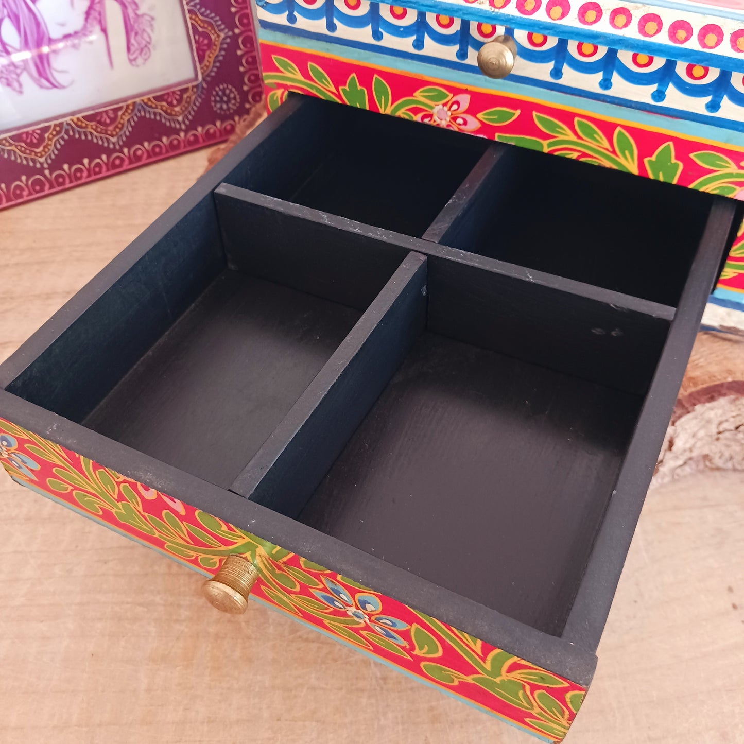 A beautiful peacock design, hand painted jewellery box in a palette of regal reds and blues made from sustainable mango wood.  This lovely box comprises a top opening section with mirror, and a single drawer; two useful compartments, accessed with discreet round knobs.