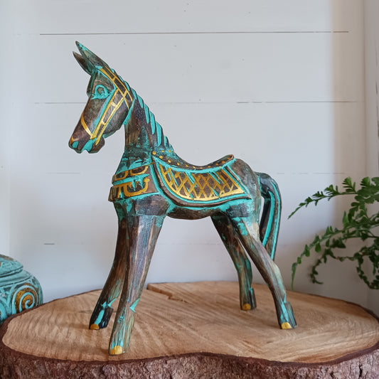 Add a touch of exotic equine elegance to your home with this beautiful hand carved decorative horse figure. Handcrafted from high-quality albasia wood in Indonesia, this striking piece features intricate carvings highlighted in gold and turquoise accents, creating a stunning contrast.