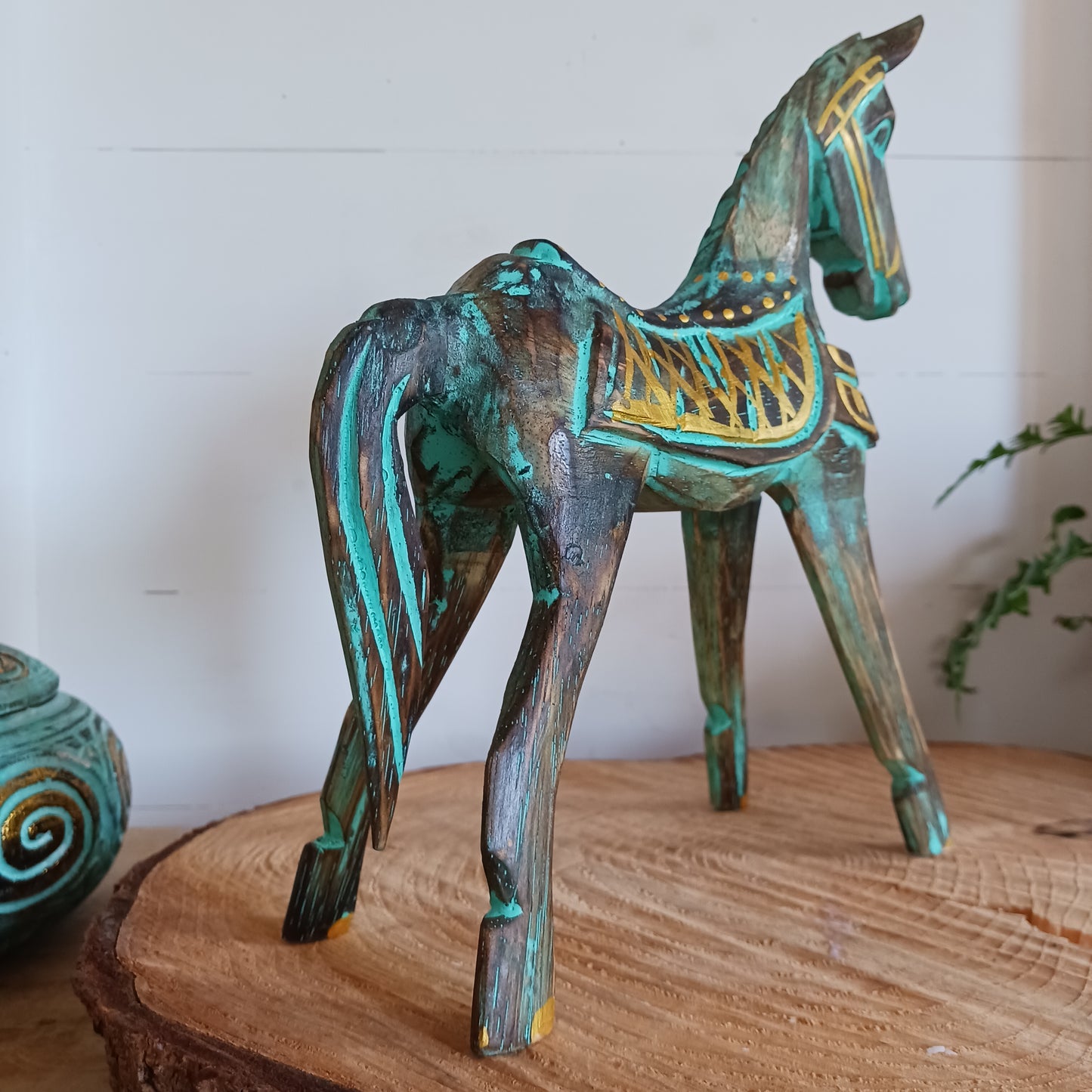 Add a touch of exotic equine elegance to your home with this beautiful hand carved decorative horse figure. Handcrafted from high-quality albasia wood in Indonesia, this striking piece features intricate carvings highlighted in gold and turquoise accents, creating a stunning contrast.