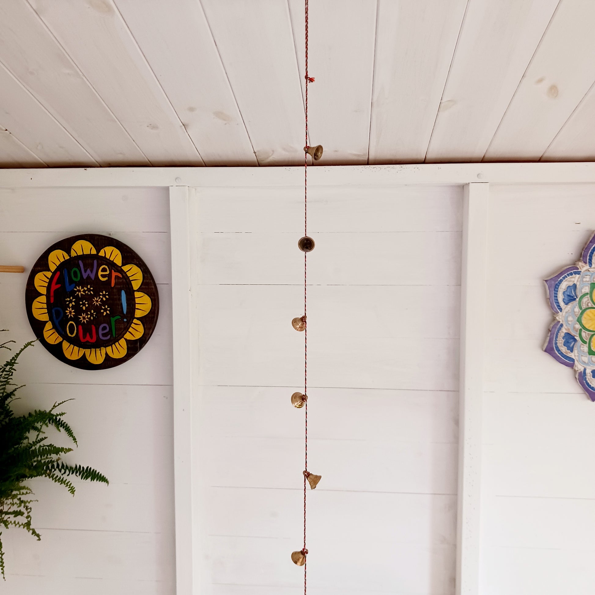 This delightful string of eleven Indian brass bells, hung on a length of rainbow coloured cord.  This lovely little string of bells makes a wonderful gentle jingle sound when hung in the breeze.