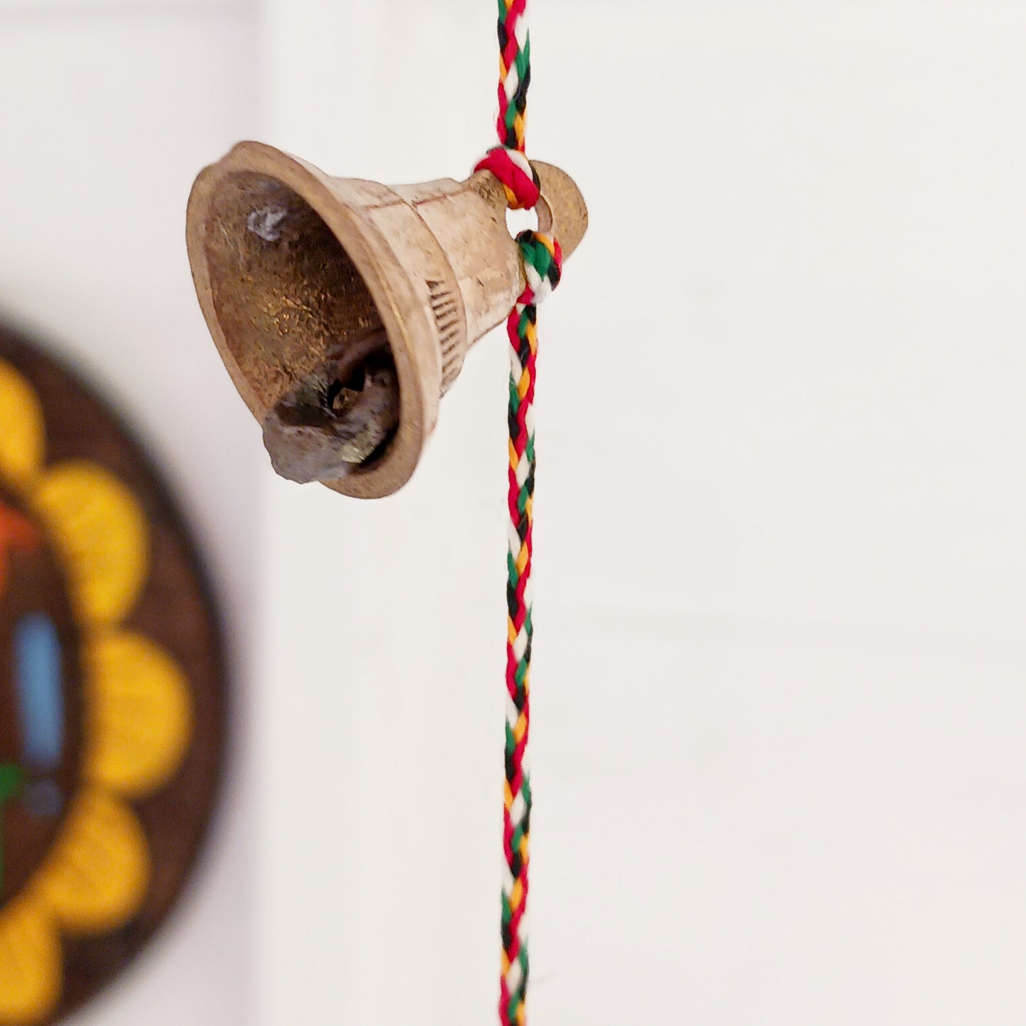 This delightful string of eleven Indian brass bells, hung on a length of rainbow coloured cord. This lovely little string of bells makes a wonderful gentle jingle sound when hung in the breeze.