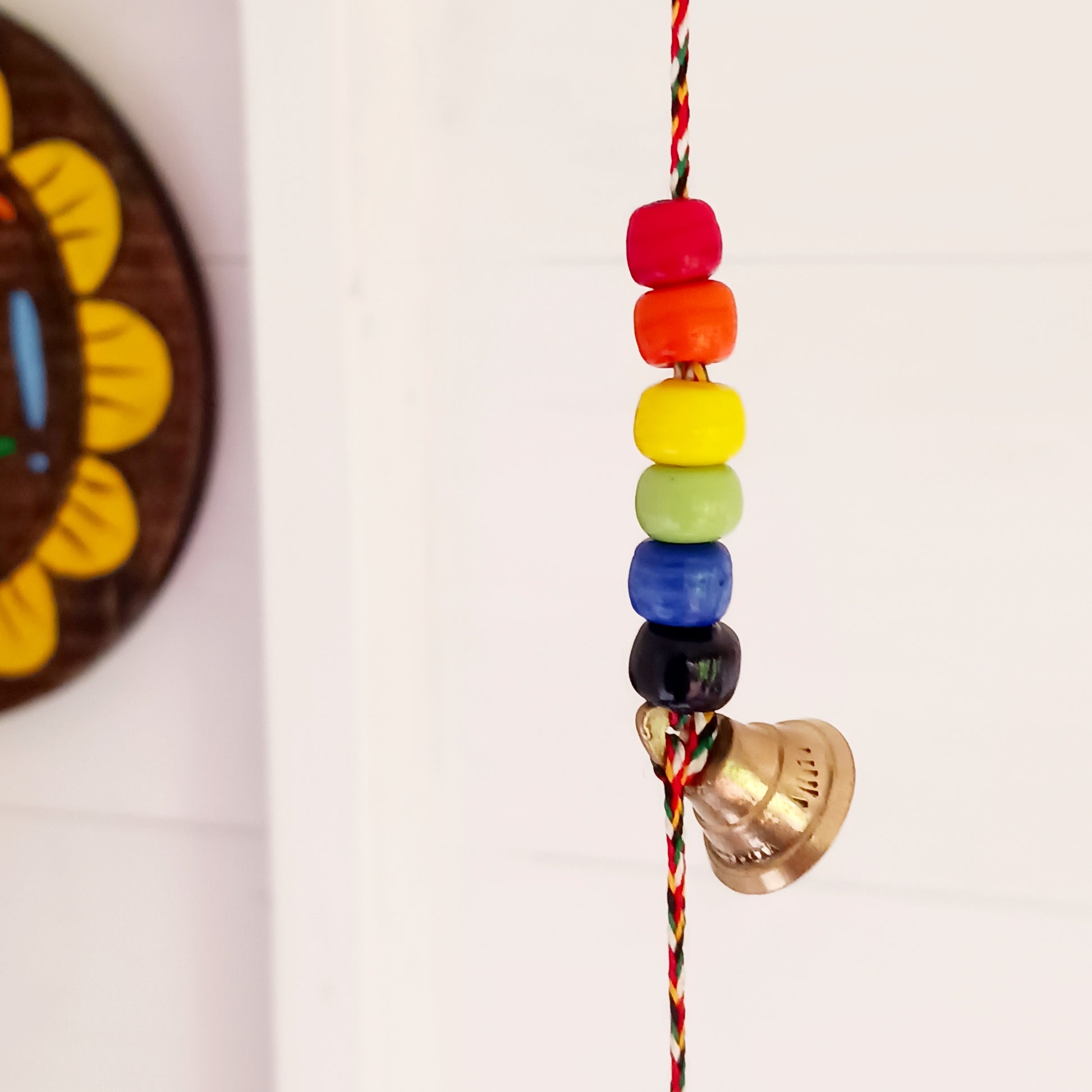 This delightful string of five Indian brass bells, hung on a length of cord have vibrant multi colour wooden beads. This lovely little string of bells makes a wonderful gentle jingle sound when hung in the breeze.