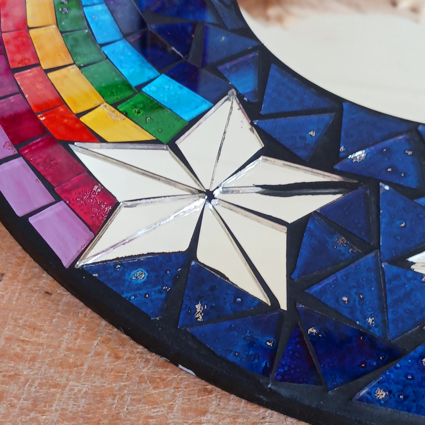 This bright and decorative round mirror is adorned with colourful mosaics creating a wonderful design of rainbow shooting stars flying through the night sky. The central area is a full mirror. Perfect to brighten up any room.