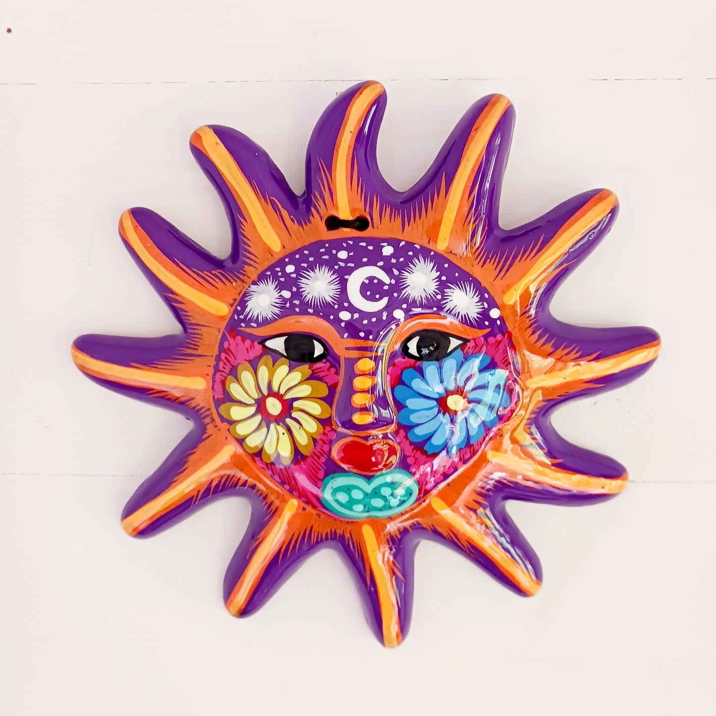 This sunny and vibrant wall plaque will get you smiling! It has been beautifully hand painted in a bright style traditional to Xalitla, a region of Guerrero, Mexico. A striking glaze adds to the bold design. It has two holes which can be used to add a hanging loop for an easy display.