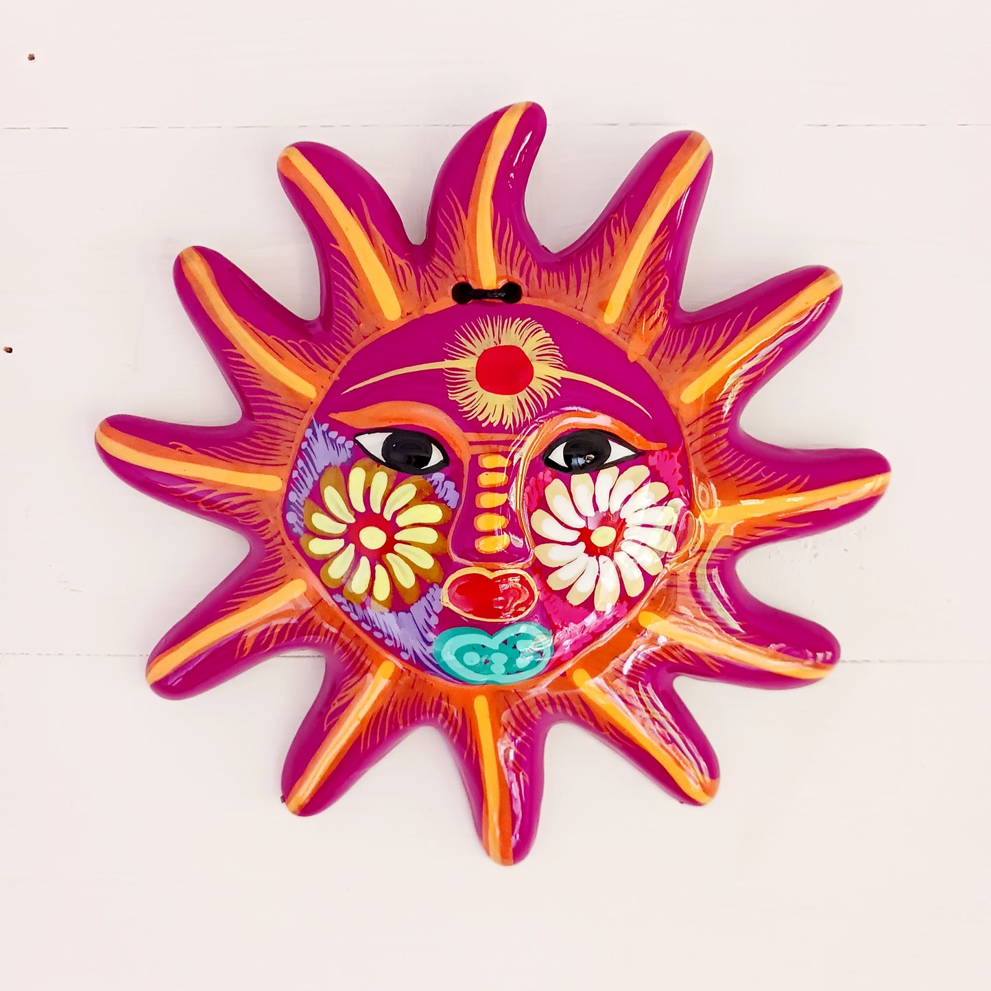 This sunny and vibrant wall plaque will get you smiling! It has been beautifully hand painted in a bright style traditional to Xalitla, a region of Guerrero, Mexico. A striking glaze adds to the bold design. It has two holes which can be used to add a hanging loop for an easy display.