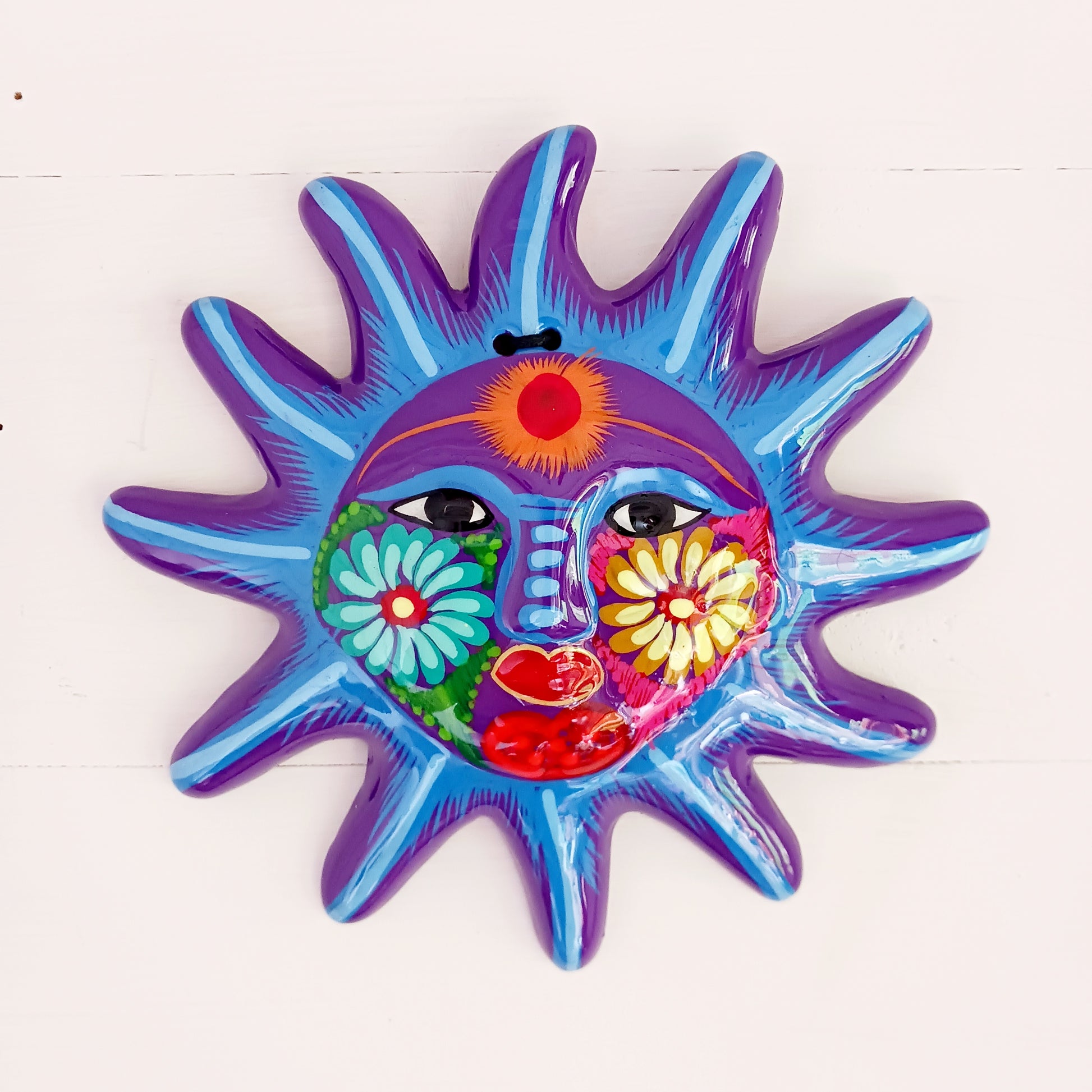 This sunny and vibrant wall plaque will get you smiling! It has been beautifully hand painted in a bright style traditional to Xalitla, a region of Guerrero, Mexico. A striking glaze adds to the bold design. It has two holes which can be used to add a hanging loop for an easy display.