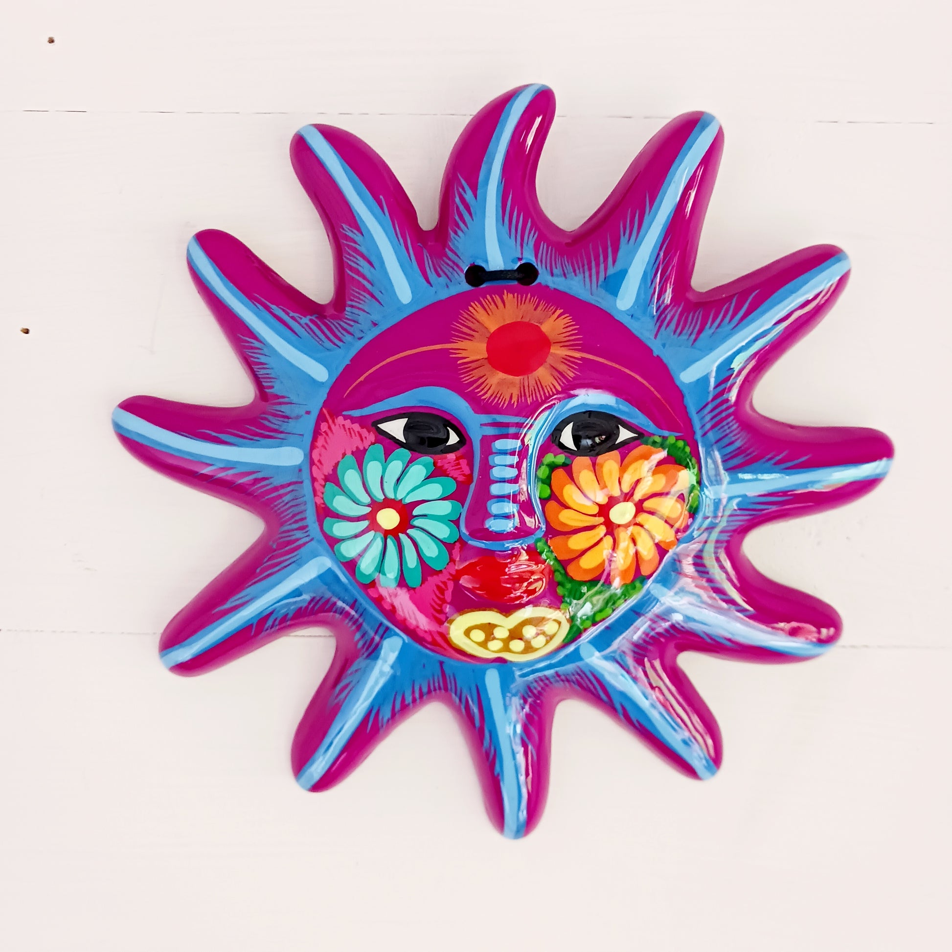 This sunny and vibrant wall plaque will get you smiling! It has been beautifully hand painted in a bright style traditional to Xalitla, a region of Guerrero, Mexico. A striking glaze adds to the bold design. It has two holes which can be used to add a hanging loop for an easy display.