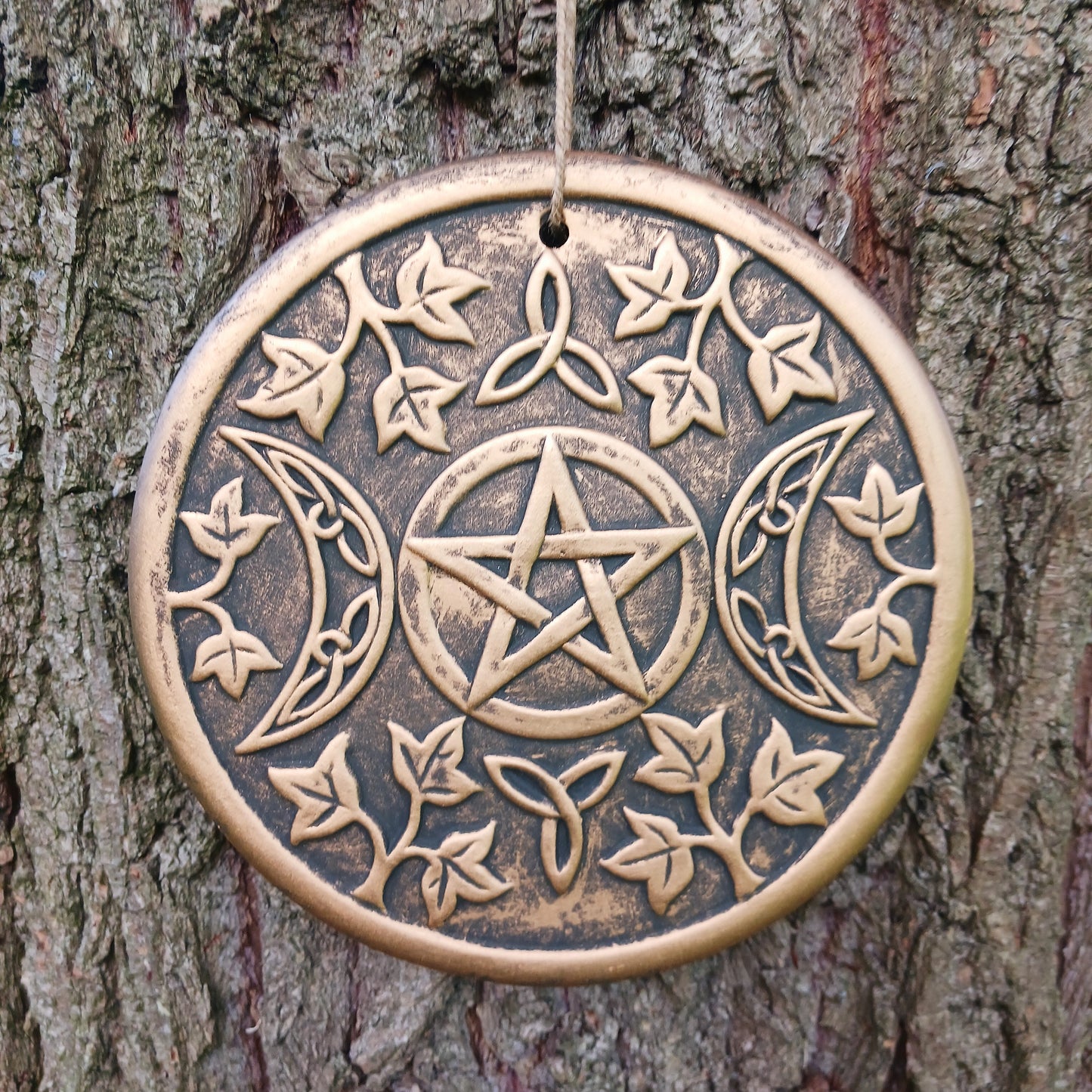 The plaque depicts a triple moon design also referred to as the triple goddess. The symbol represents the Maiden, Mother and Crone as the waxing, full and waning moon and is often related to feminine energy and psychic abilities.