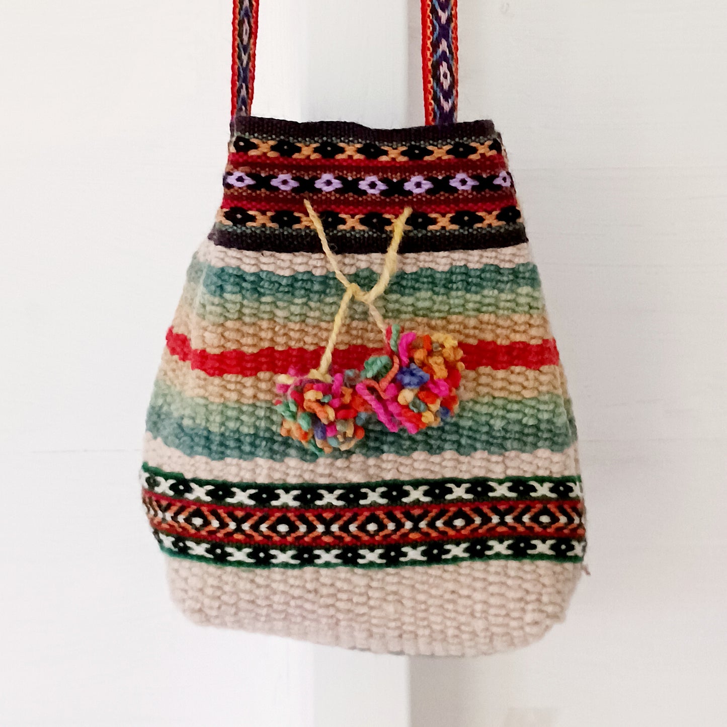 This cute sheepswool drawstring bag has been created using naturally dyed colourful wools to create handy sized day bag, perfect for carrying your purse and keys, and as a festival bag. Two pom poms have been added as a finishing touch. The bag itself is fully lined and the straps have been made using traditional manta fabrics. Inside is cotton lined.