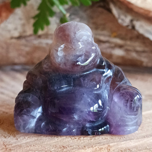 This beautiful miniature handcarved Laughing Buddha has been crafted from genuine Amethyst.  This gemstone Buddha is a jolly and elegant symbol of peace, spiritual growth, and inner clarity.