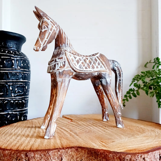 Handcrafted from albasia wood, this antique horse features intricate carvings and a beautiful distressed finish, exuding a timeless charm that appeals to all. Ideal for adding a touch of vintage elegance to any space, this piece is versatile enough to complement various interior styles. Its compact size ensures it fits seamlessly on shelves, mantels, or as part of a centerpiece.