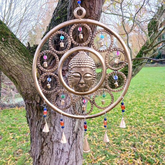 Enhance your living space with this beautiful large Buddha face 15 bell chimes.  This lovely brass decoration exudes serenity and spiritual charm. An intricate piece featuring a serene Buddha face surrounded by delicate circular accents and vibrant, colourful beads. With 15 brass bells, this chime creates a harmonious, soothing sound, making it ideal for both indoor and outdoor spaces.