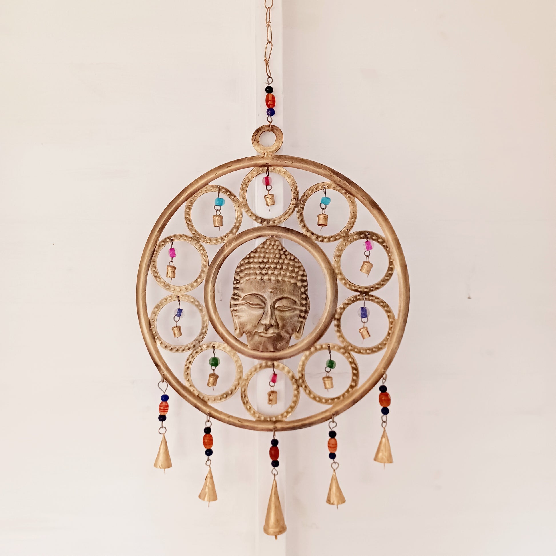 Enhance your living space with this beautiful large Buddha face 15 bell chimes.  This lovely brass decoration exudes serenity and spiritual charm. An intricate piece featuring a serene Buddha face surrounded by delicate circular accents and vibrant, colourful beads. With 15 brass bells, this chime creates a harmonious, soothing sound, making it ideal for both indoor and outdoor spaces.