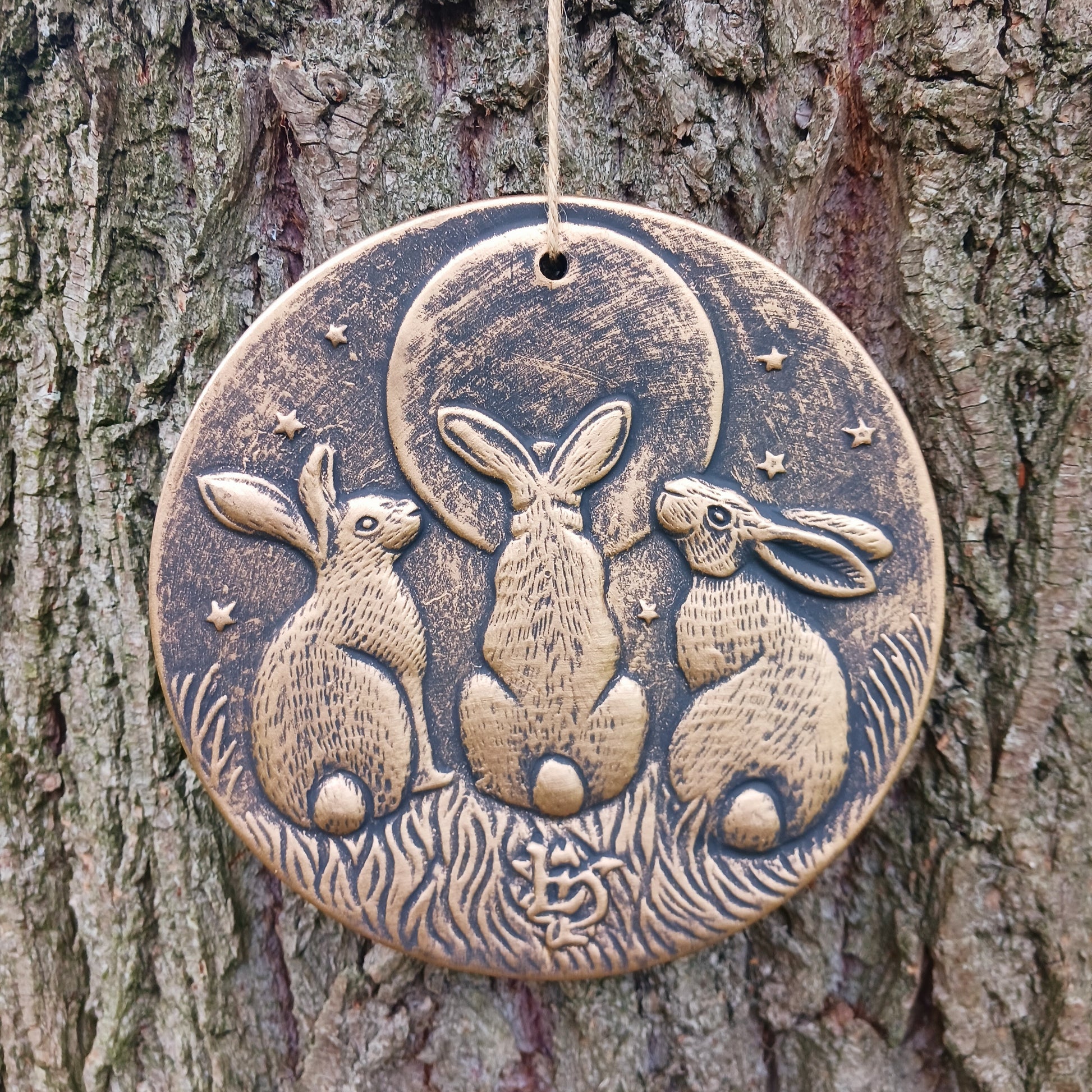 A stunning terracotta wall plaque with a bronze-like effect and striking motif of three moon-gazing hares. The hare and moon have been associated with each other for centuries, and are often depicted together in art. Together, the hare and moon can represent good fortune, abundance, and positive energies.