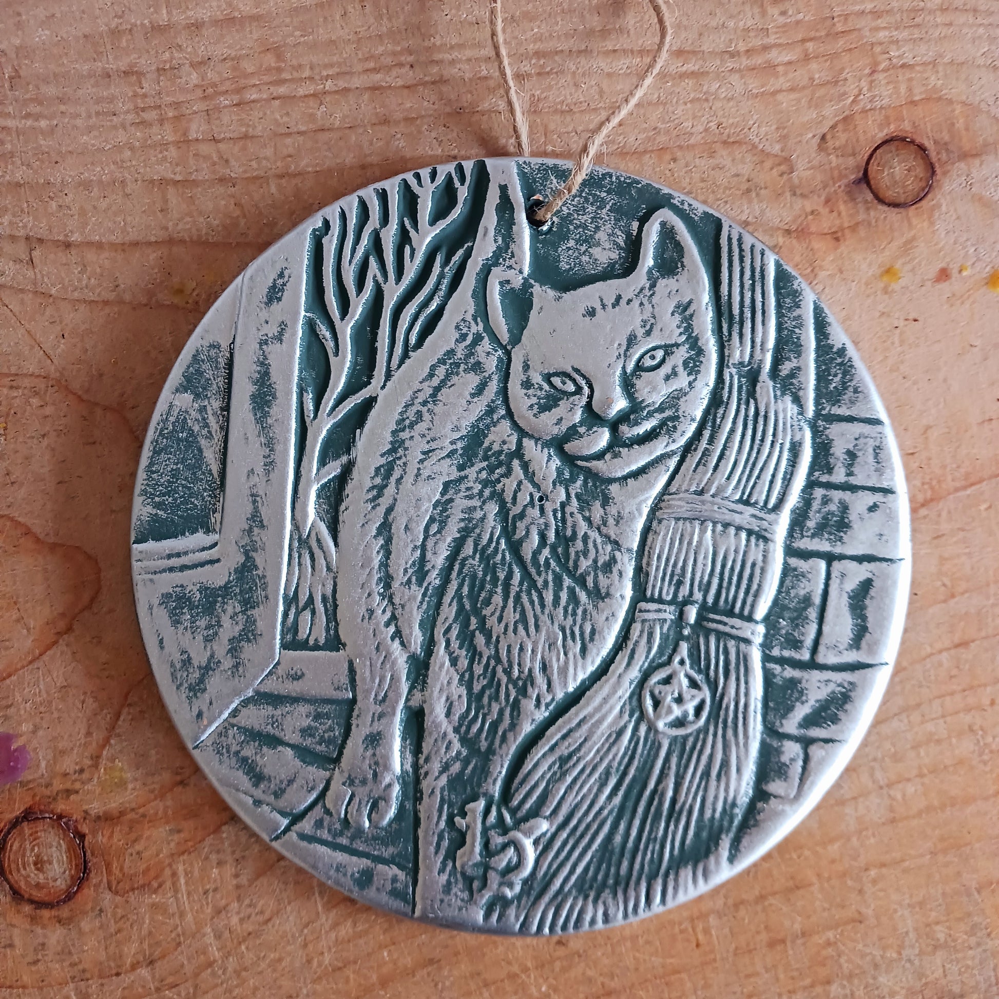 This stunning terracotta wall plaque has a silver-like finish with Lisa Parker's 'A Brush With Magic' artwork featuring a cat and witch's broom.