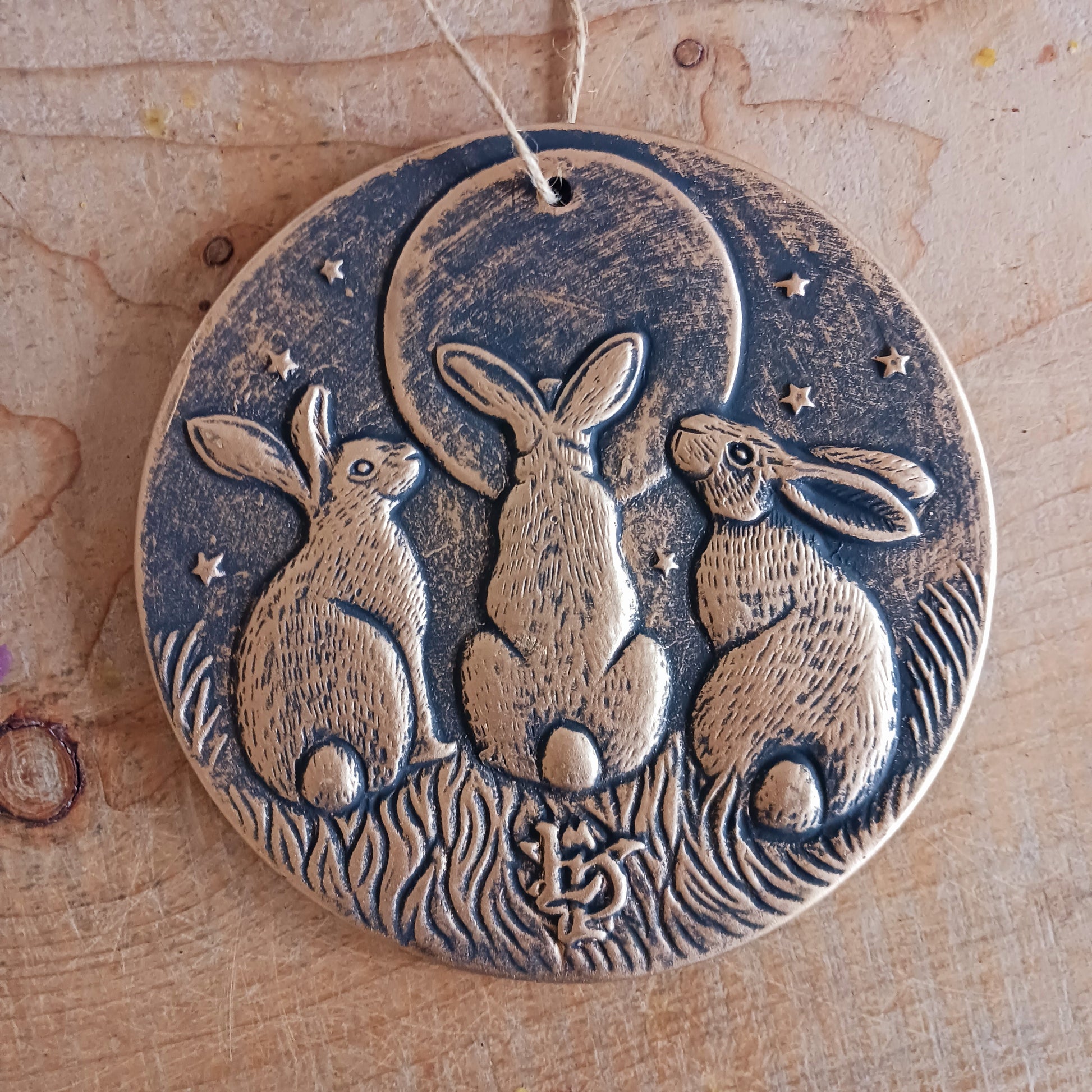 A stunning terracotta wall plaque with a bronze-like effect and striking motif of three moon-gazing hares. The hare and moon have been associated with each other for centuries, and are often depicted together in art. Together, the hare and moon can represent good fortune, abundance, and positive energies.