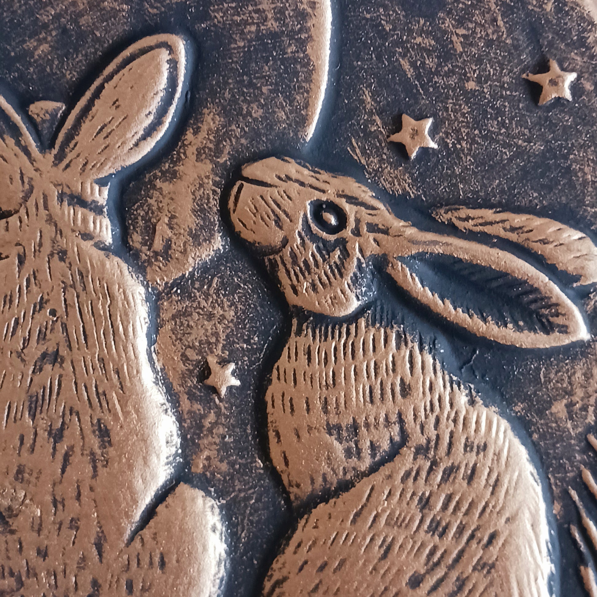 A stunning terracotta wall plaque with a bronze-like effect and striking motif of three moon-gazing hares. The hare and moon have been associated with each other for centuries, and are often depicted together in art. Together, the hare and moon can represent good fortune, abundance, and positive energies.