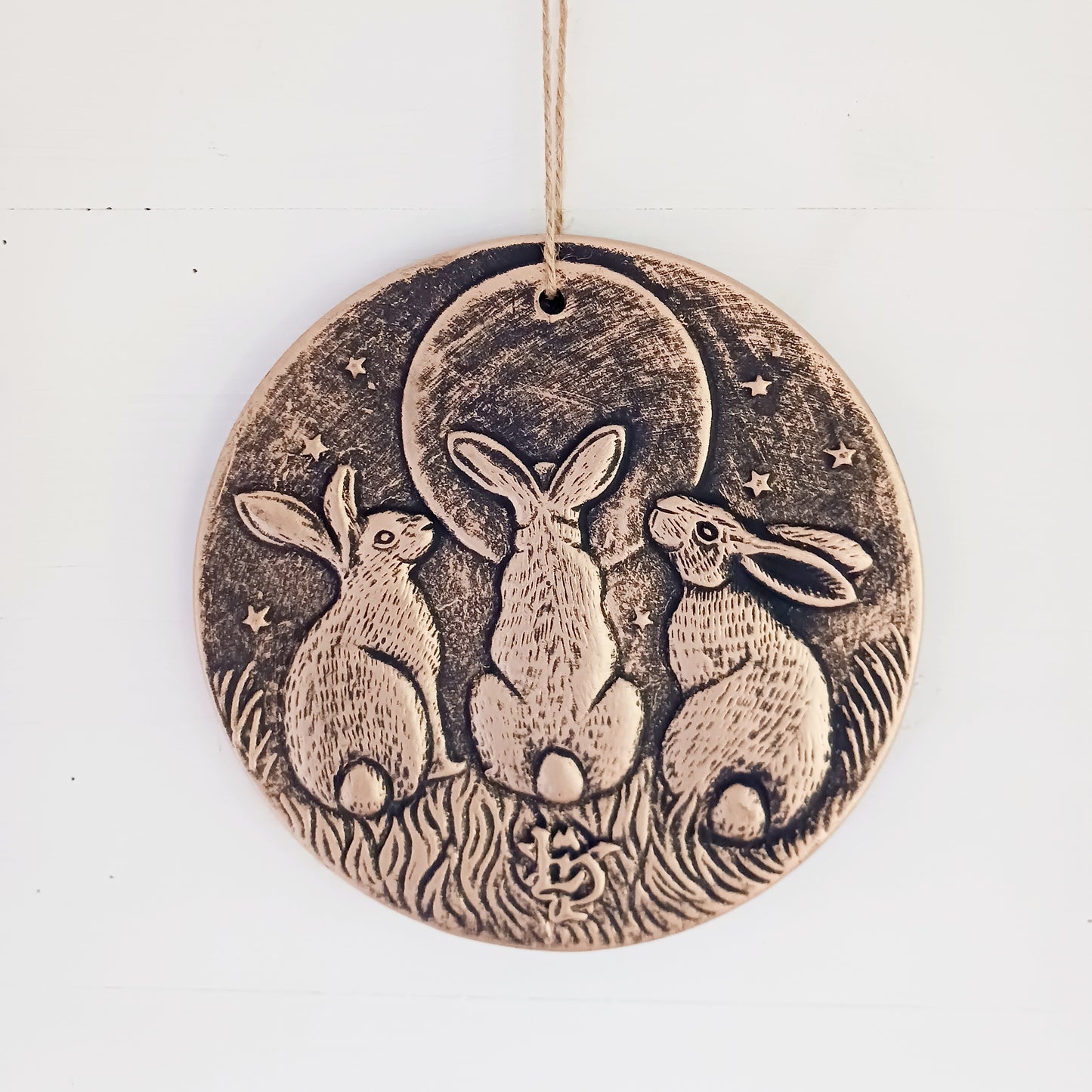 A stunning terracotta wall plaque with a bronze-like effect and striking motif of three moon-gazing hares. The hare and moon have been associated with each other for centuries, and are often depicted together in art. Together, the hare and moon can represent good fortune, abundance, and positive energies.