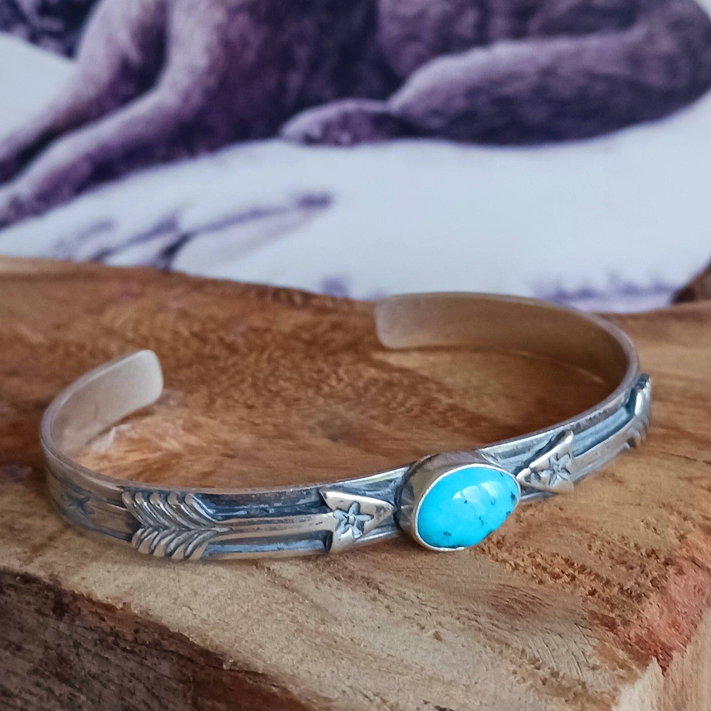 This bracelet is a stunning example of classic Navajo jewellery. This piece is handmade out of sterling silver and genuine Turquoise oval stone.  The Arrows are for protection.