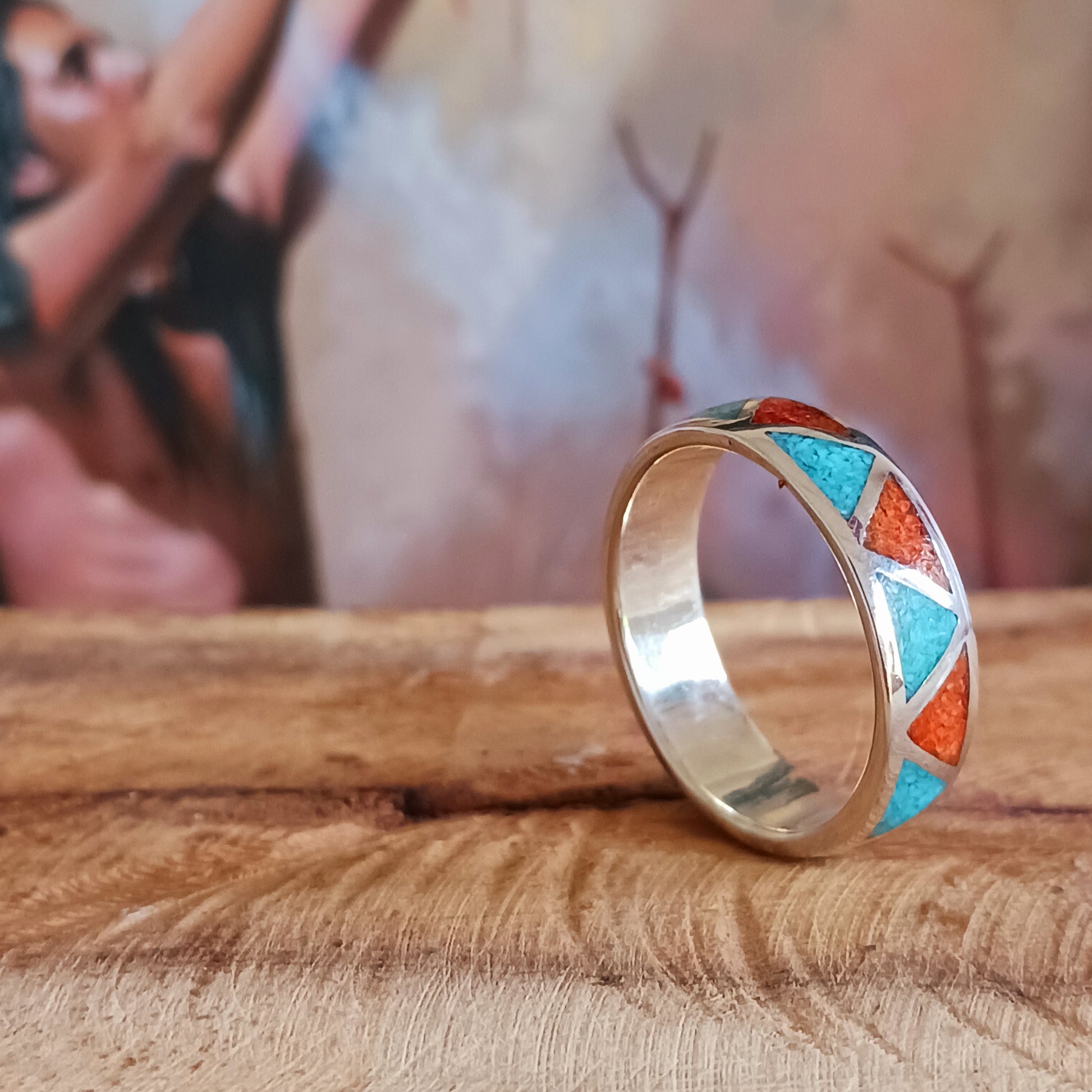 This beautiful inlaid Silver Turquoise Coral Navajo Ring offers a traditional, Native American pattern. Opposing triangles are fitted with hand crushed, gemstone chips. Set in Sterling Silver, this ring offers a smooth flat surface that will fit comfortably on your finger or thumb.  Perfect for his and her bands, this inlaid Silver Turquoise Coral Navajo Ring is a nice contrast for any occasion.