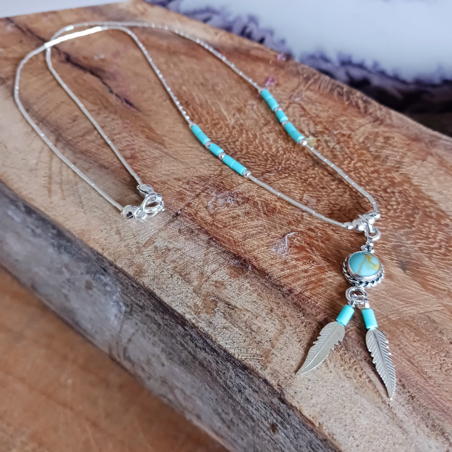 This Turquoise Silver feather necklace is a stunning piece of boho style jewellery featuring an authentic Native American design with a turquoise stone and two silver feathers. This beautiful pendant makes a meaningful gift, blending cultural heritage with personalized elegance.