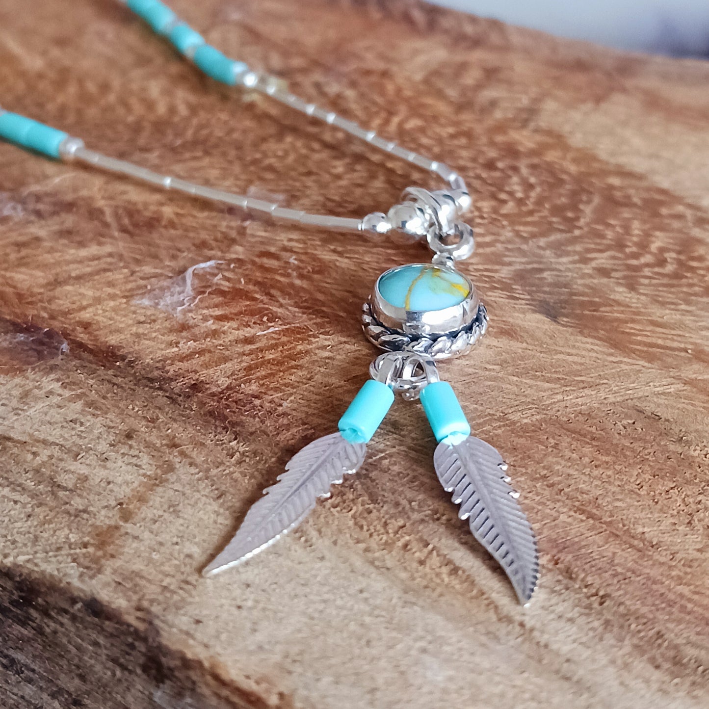 This Turquoise Silver feather necklace is a stunning piece of boho style jewellery featuring an authentic Native American design with a turquoise stone and two silver feathers. This beautiful pendant makes a meaningful gift, blending cultural heritage with personalized elegance.