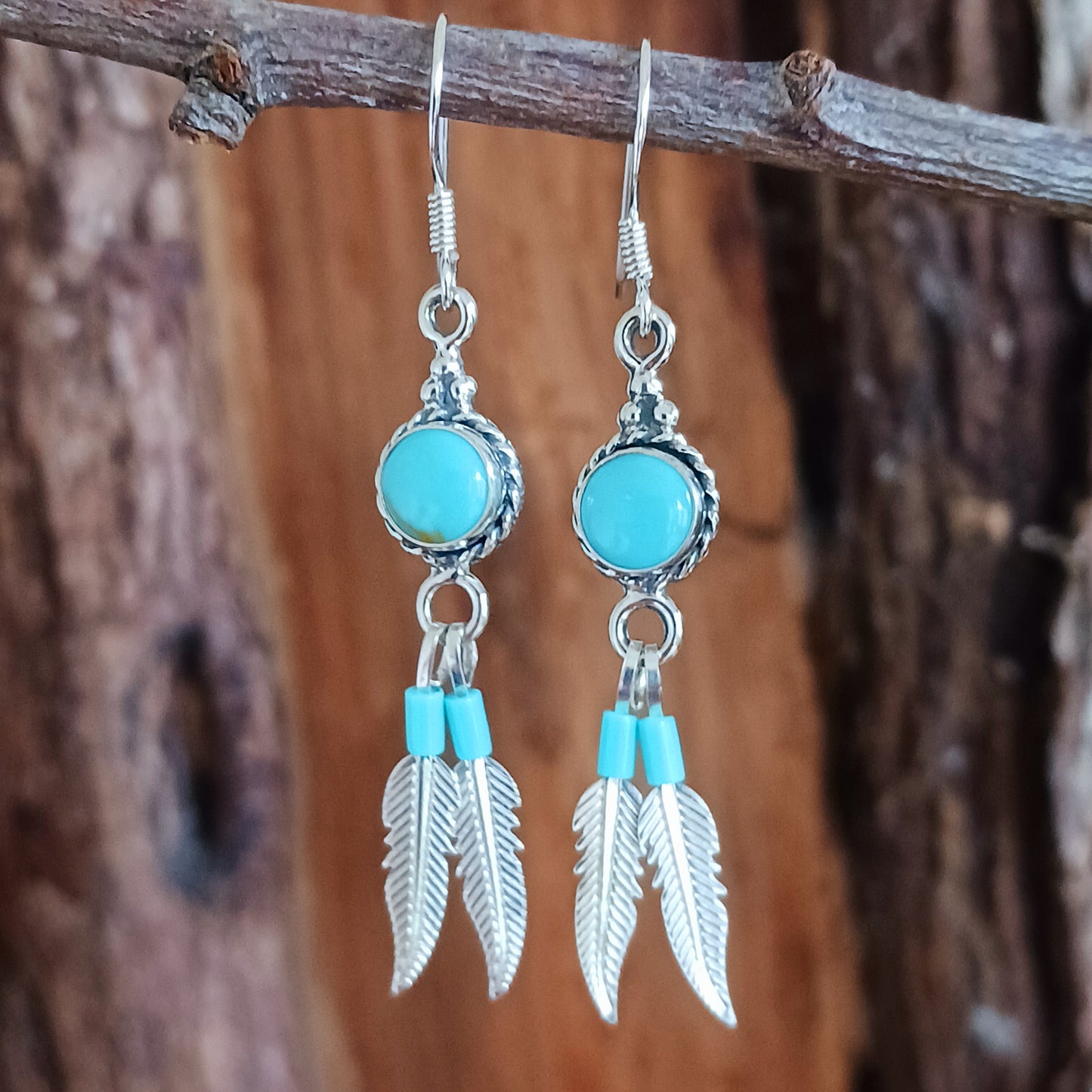 These sterling silver and turquoise feather dangle earrings are handmade in Native American style. The earrings measure approximately 25mm in length from top of hook to bottom of feather. All silver parts of the earrings are solid sterling silver, and the stone is Kingsman Turquoise.