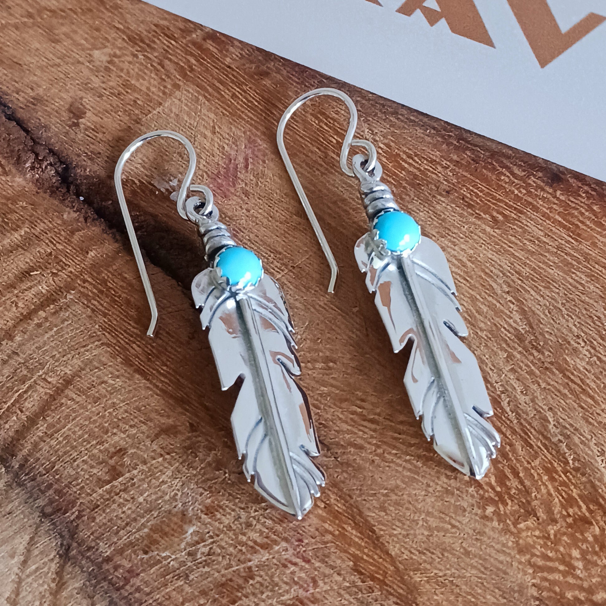 These are exquisite Navajo solid silver earrings, handmade by Navajo artist, Lula Nez. The feather earrings are hand cut with natural Kingsman Turquoise stone.  Feather is a totem of the all-powerful eagle and a gift of feather is a great honour.