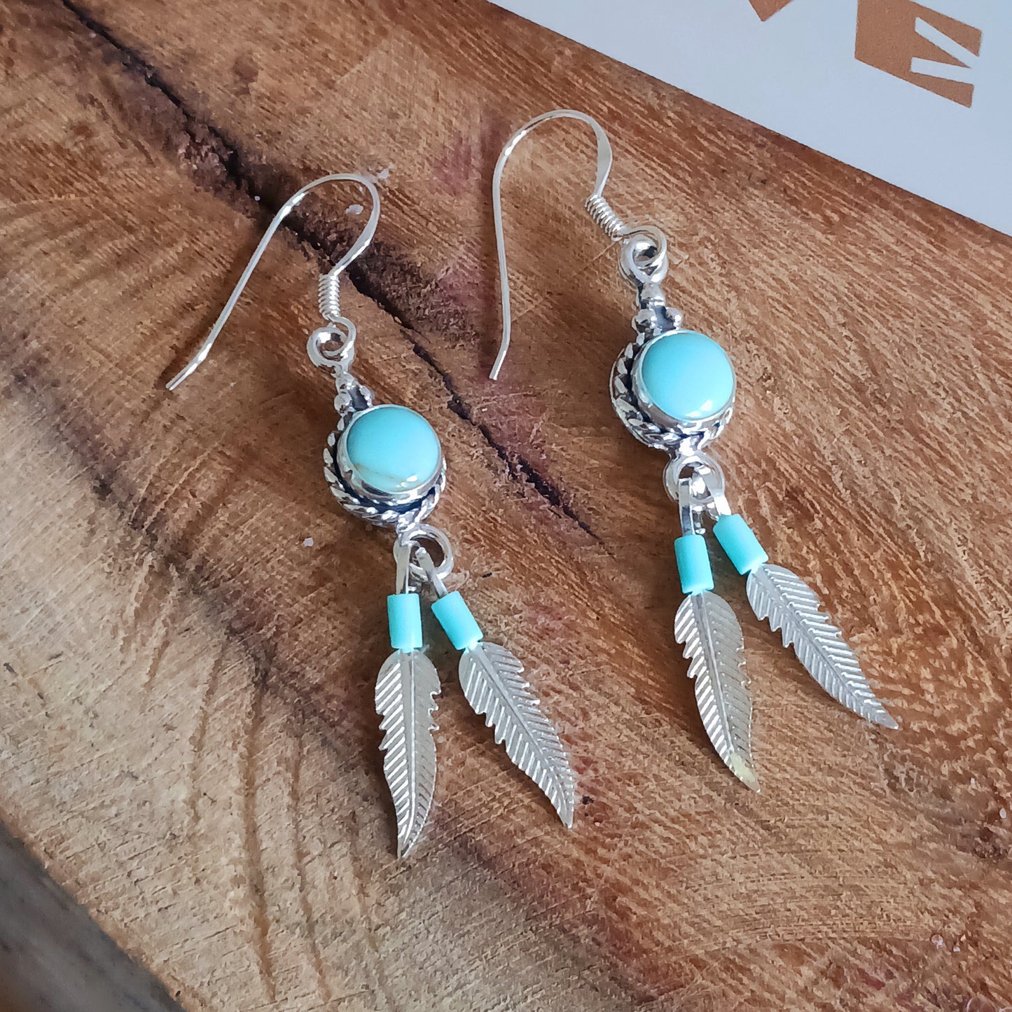 These sterling silver and turquoise feather dangle earrings are handmade in Native American style. The earrings measure approximately 25mm in length from top of hook to bottom of feather. All silver parts of the earrings are solid sterling silver, and the stone is Kingsman Turquoise.