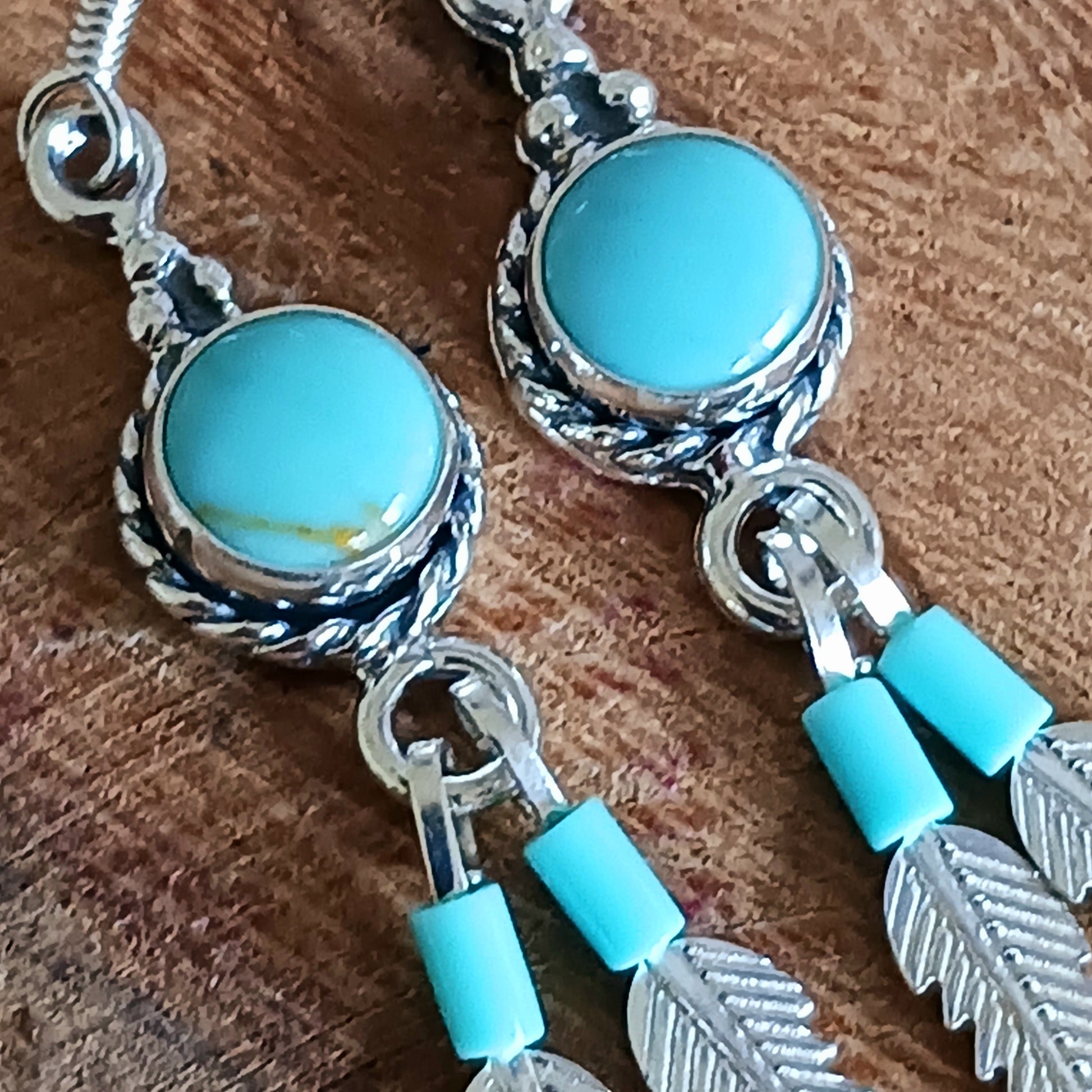 These sterling silver and turquoise feather dangle earrings are handmade in Native American style. The earrings measure approximately 25mm in length from top of hook to bottom of feather. All silver parts of the earrings are solid sterling silver, and the stone is Kingsman Turquoise.